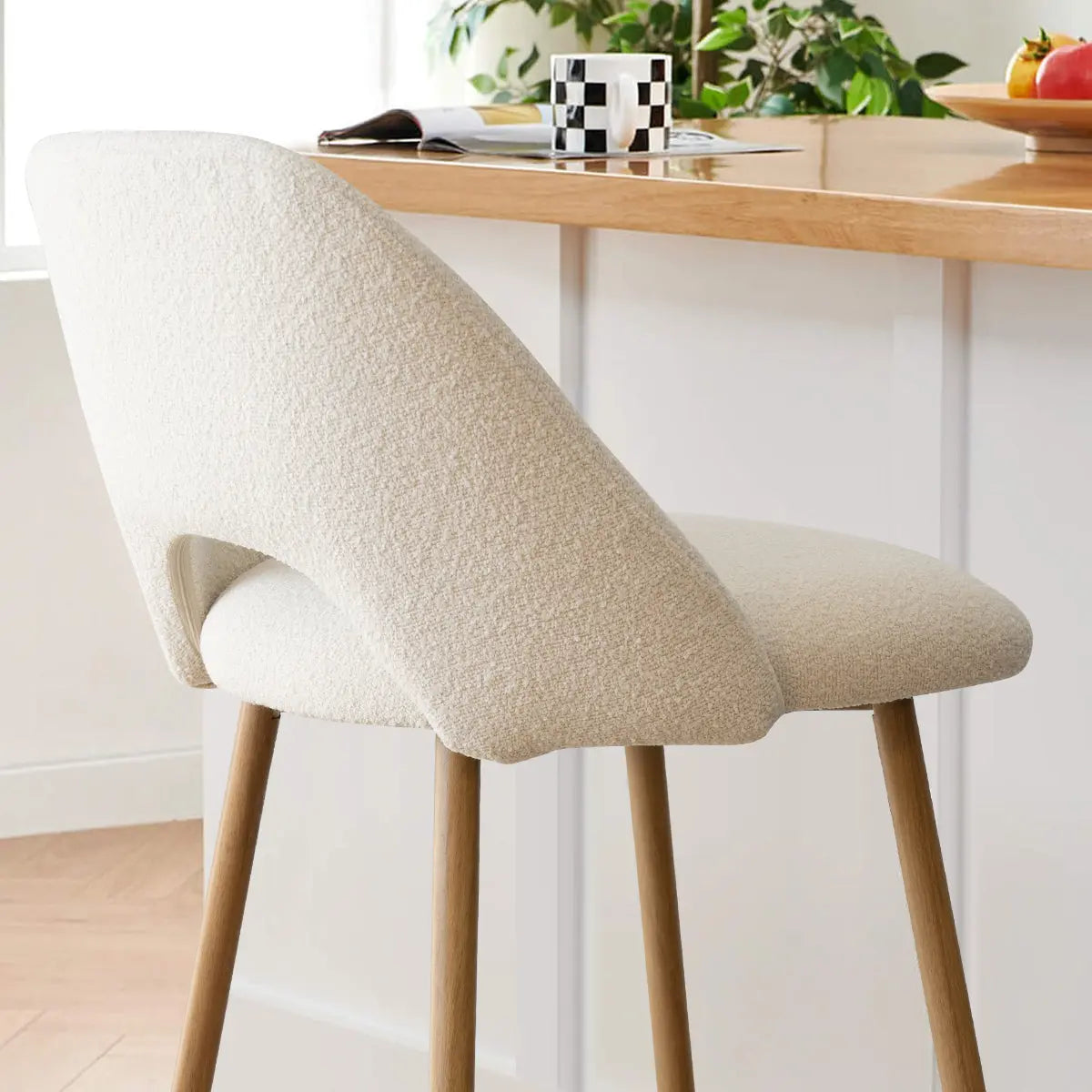 Edwin Modern Boucle Counter Stool in light kitchen with wood countertop, neutral walls, and chevron flooring.