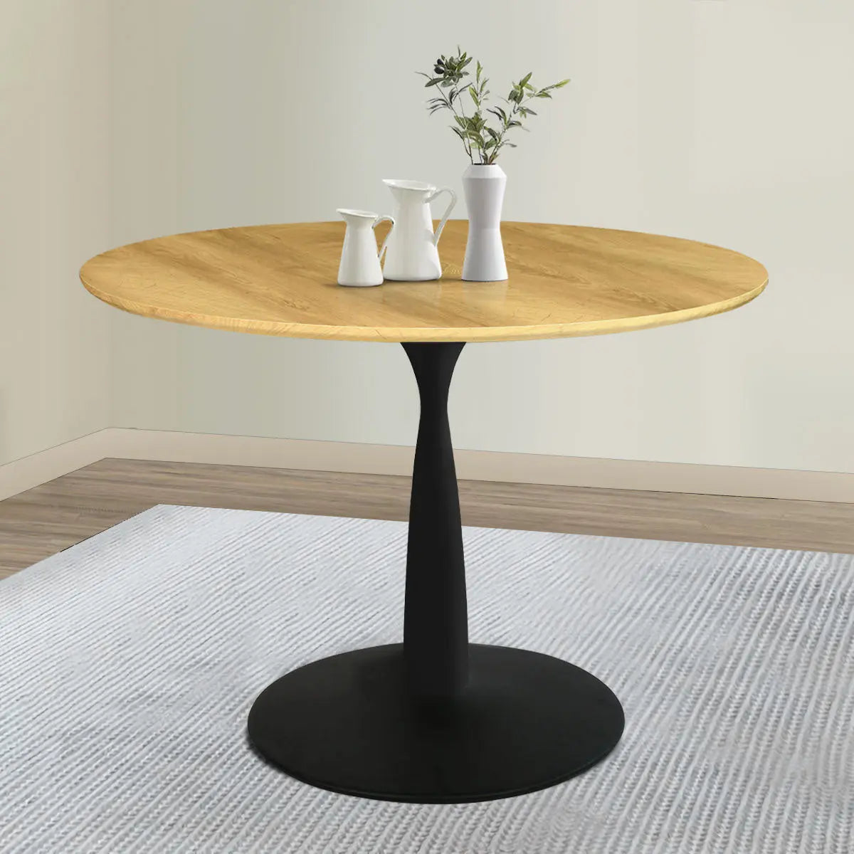 Modern oak round pedestal dining table, light wood flooring, soft beige walls, cozy dining room setting.