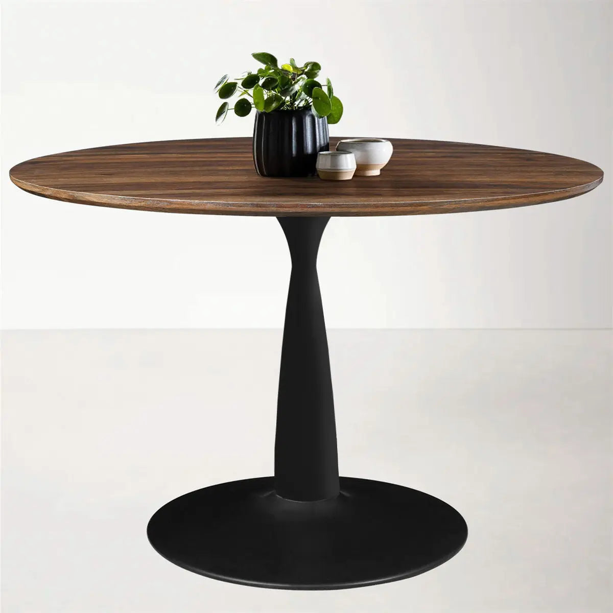 Harold Modern Round Pedestal Dining Table with black base, wooden top, in minimalist setting.