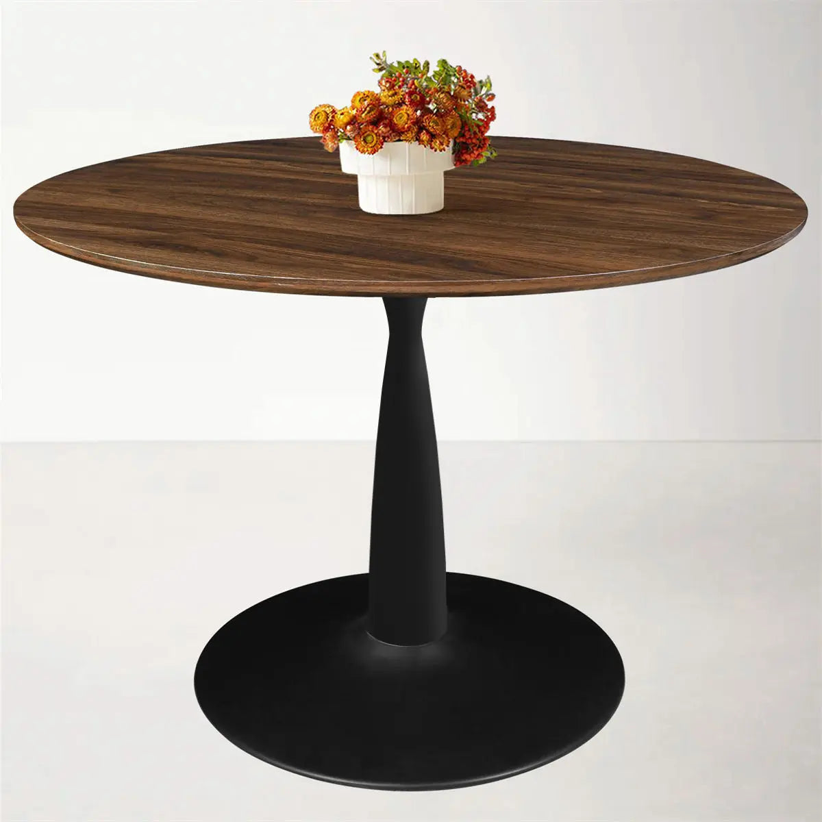 Harold Modern Round Pedestal Dining Table with dark pedestal base, wooden top, white wall background.