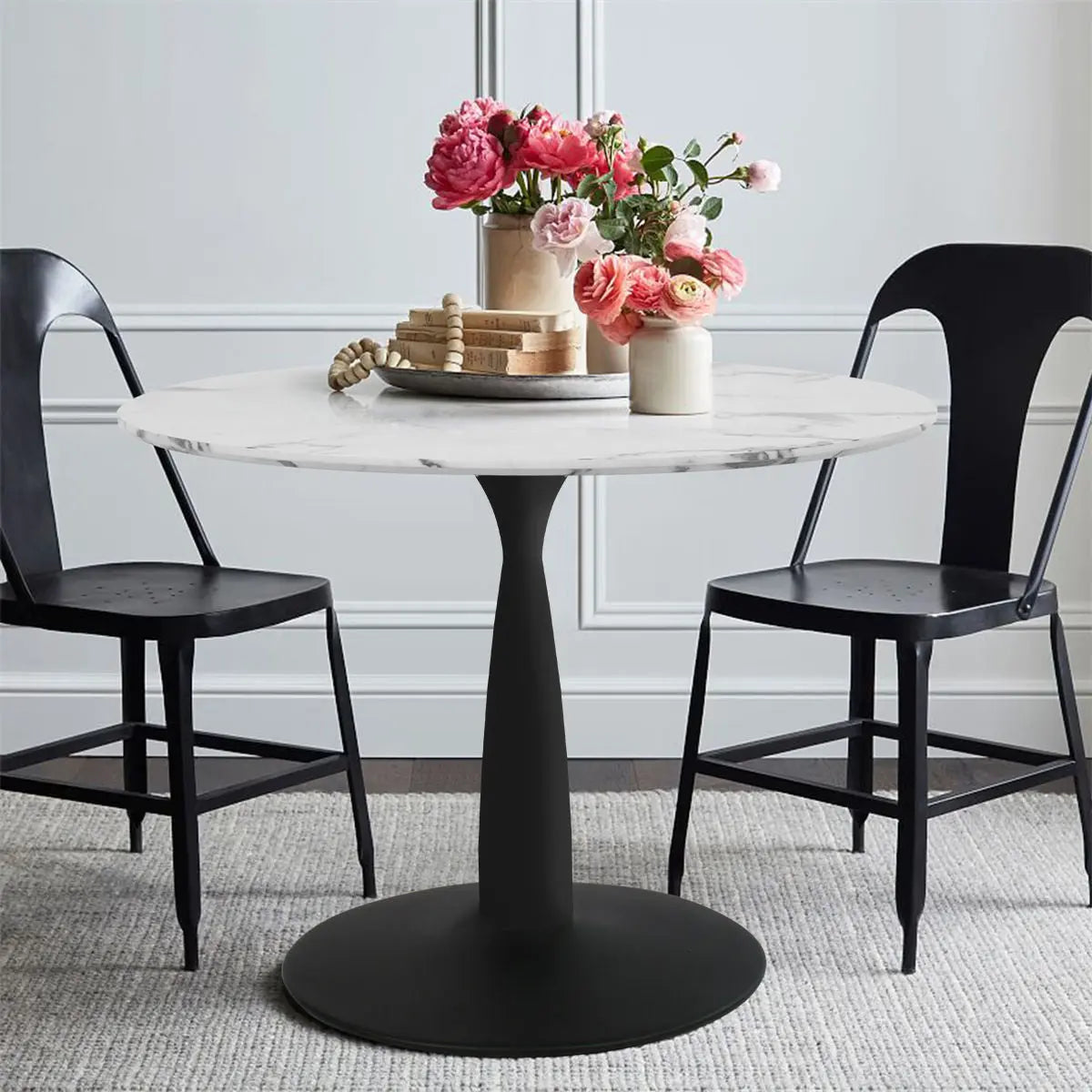 Harris faux marble top pedestal dining table with black chairs, gray walls, and carpeted floor.