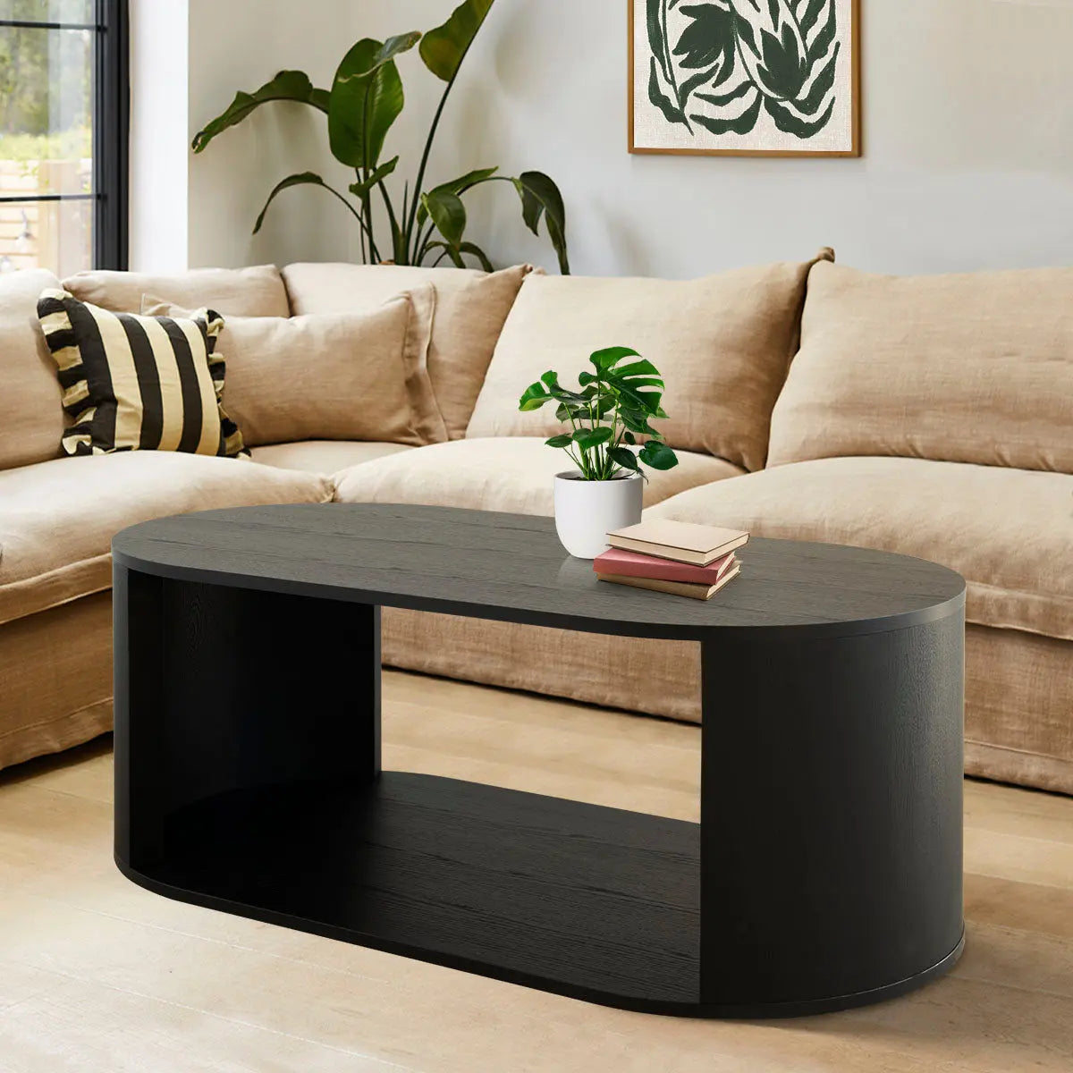 Hobo Modern Black Oval Coffee Table with beige sofa, light wood flooring, and minimalist wall art.