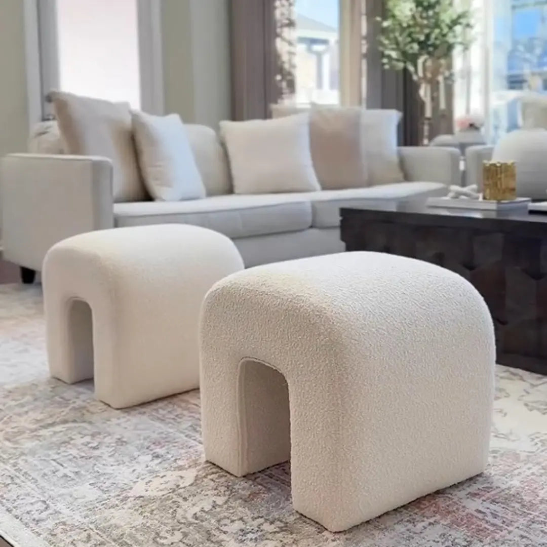 Beige boucle ottoman with waterfall design, beige sofa, patterned rug, modern living room decor.