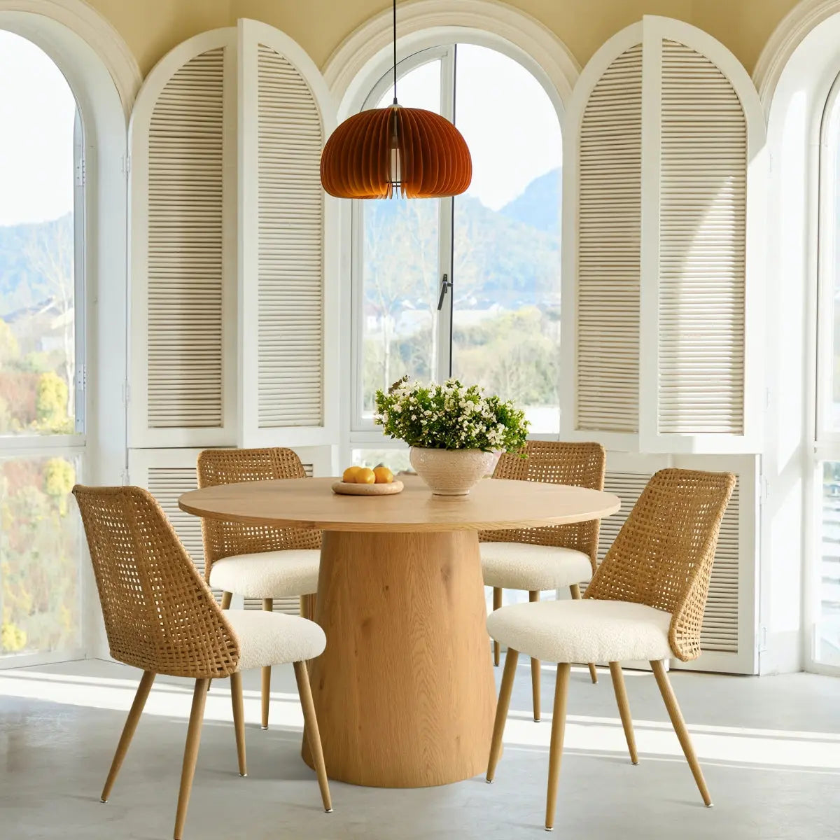 Dwen & Nice round rattan dining set in sunny room with arched shutters and beige walls.