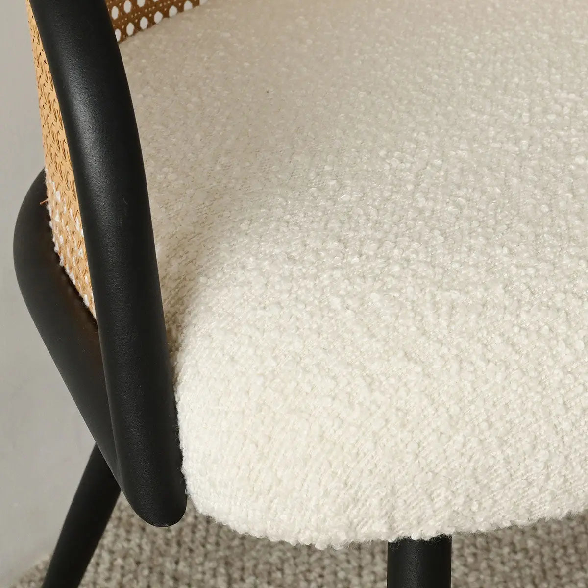 Close-up of chair detail from Oliver & Jules Rattan Round Dining Table Set on textured carpet.