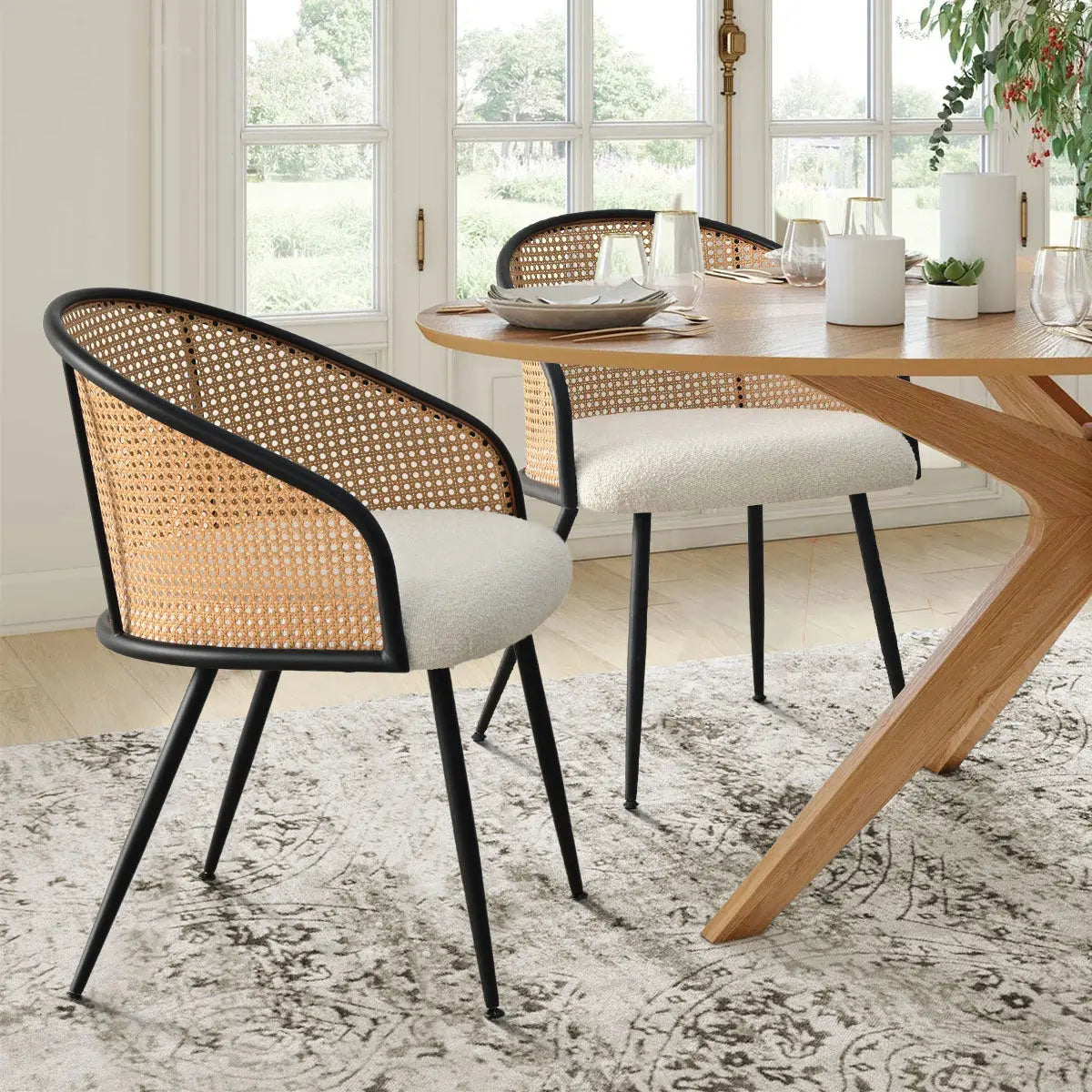 Jules Modern Upholstered Rattan Dining Chair with oak table, patterned rug, and large windows.