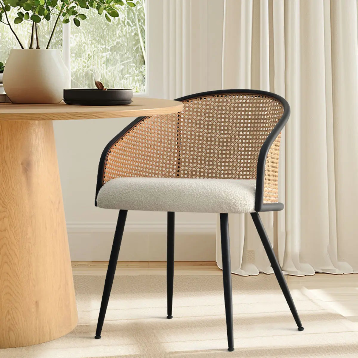 Jules Modern Upholstered Rattan Dining Chair with Arms, wooden table, neutral curtains, cozy dining room.