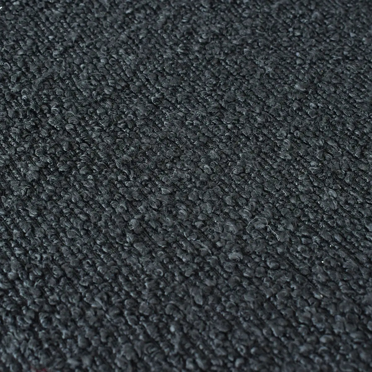 Close-up of dark textured fabric or carpet upholstery; no visible Jules Modern Upholstered Rattan Dining Chair.