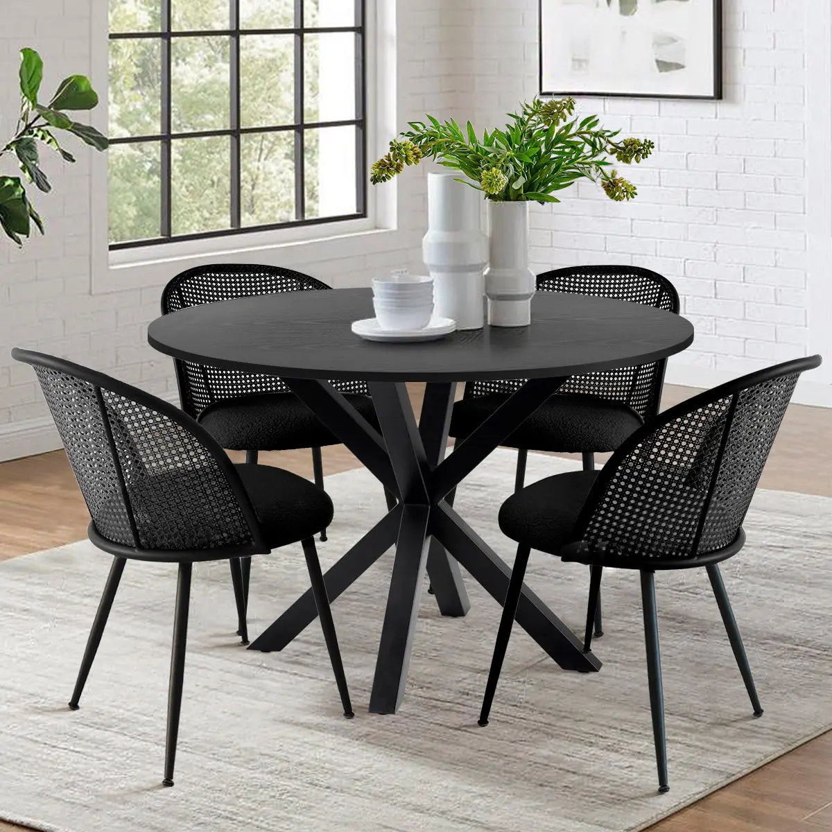 Oliver & Jules Modern Black Round Dining Table Set in dining room with white brick wall, rug flooring.