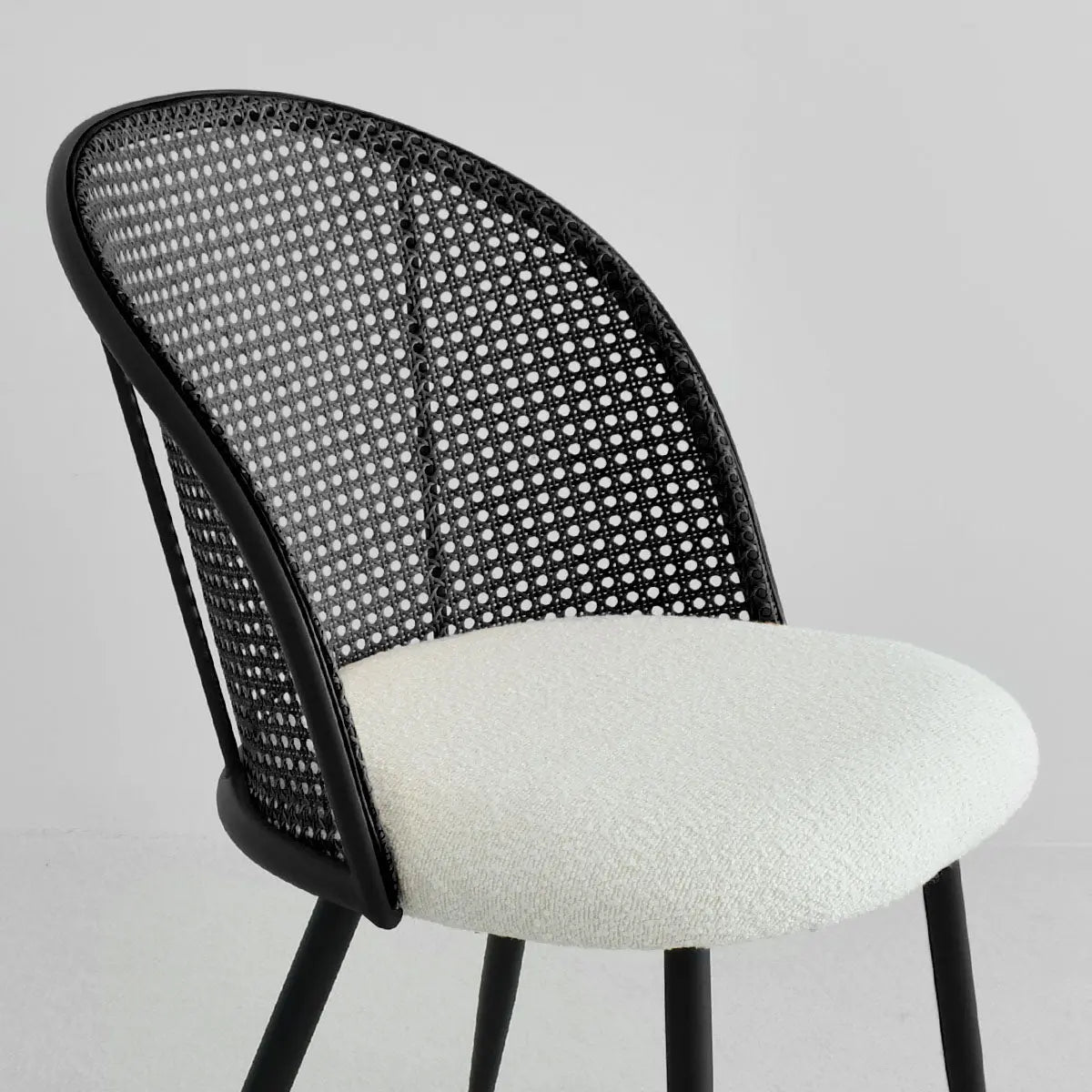 Jules Modern Upholstered Rattan Dining Chair with black frame and white cushion in neutral room.