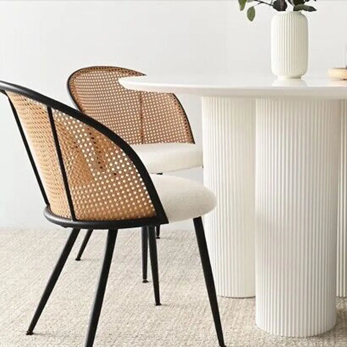 Modern upholstered rattan dining chair with white table in neutral room, textured flooring.