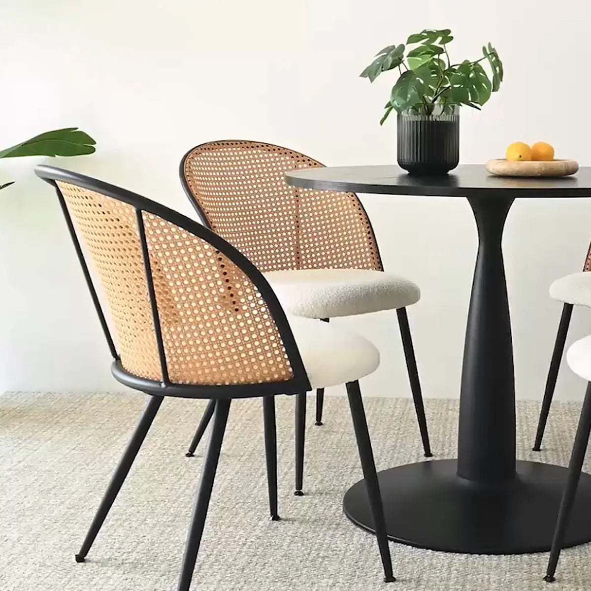 Jules Modern Upholstered Rattan Dining Chair in room with black table, textured carpet flooring.