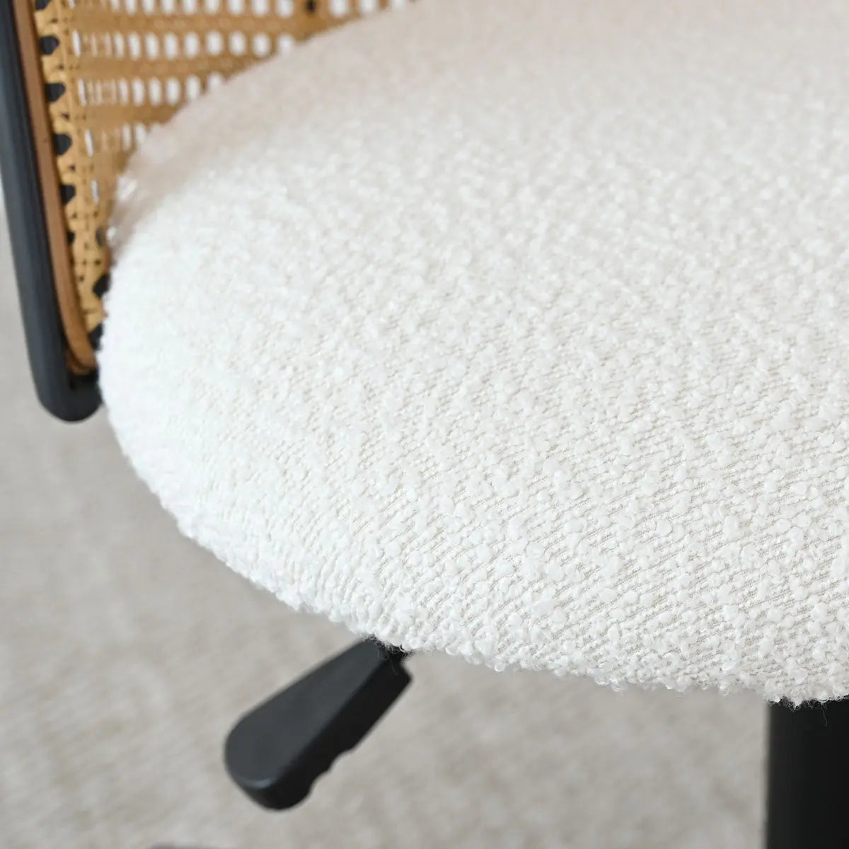 Close-up of Jules Modern Upholstered Rattan Swivel Office Chair on neutral textured carpet flooring.