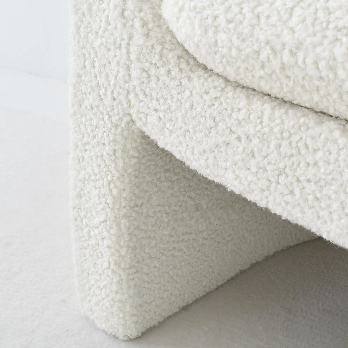 Close-up of cream-tinted Kiki Boucle Accent Chair fabric and textured base. Modern design detail.