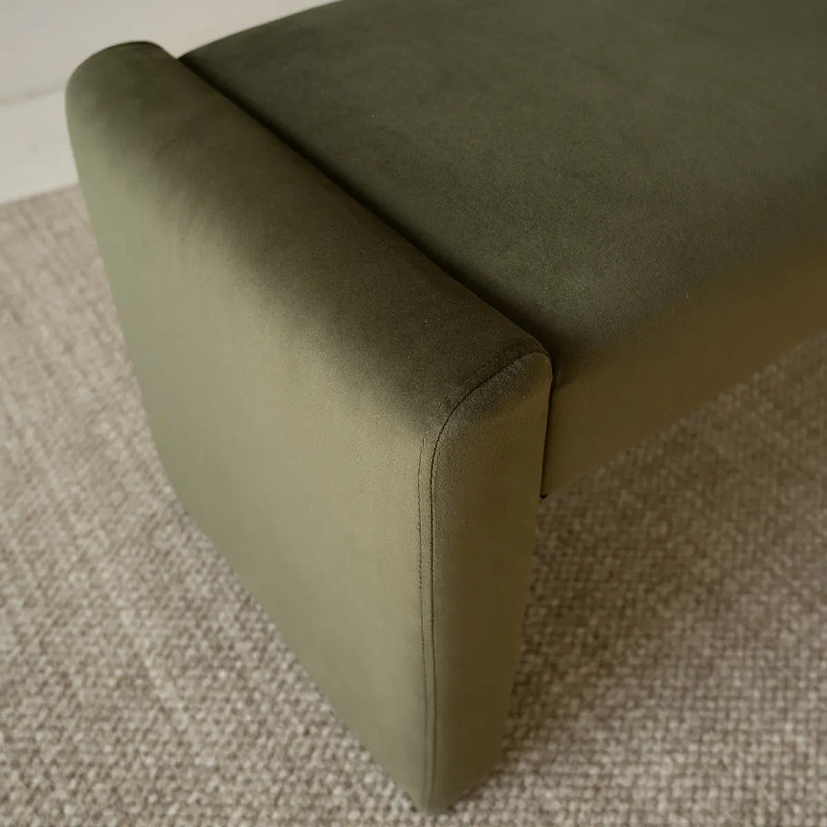 Kaia green modern leather velvet waterfall bench on beige carpeting, close-up view.