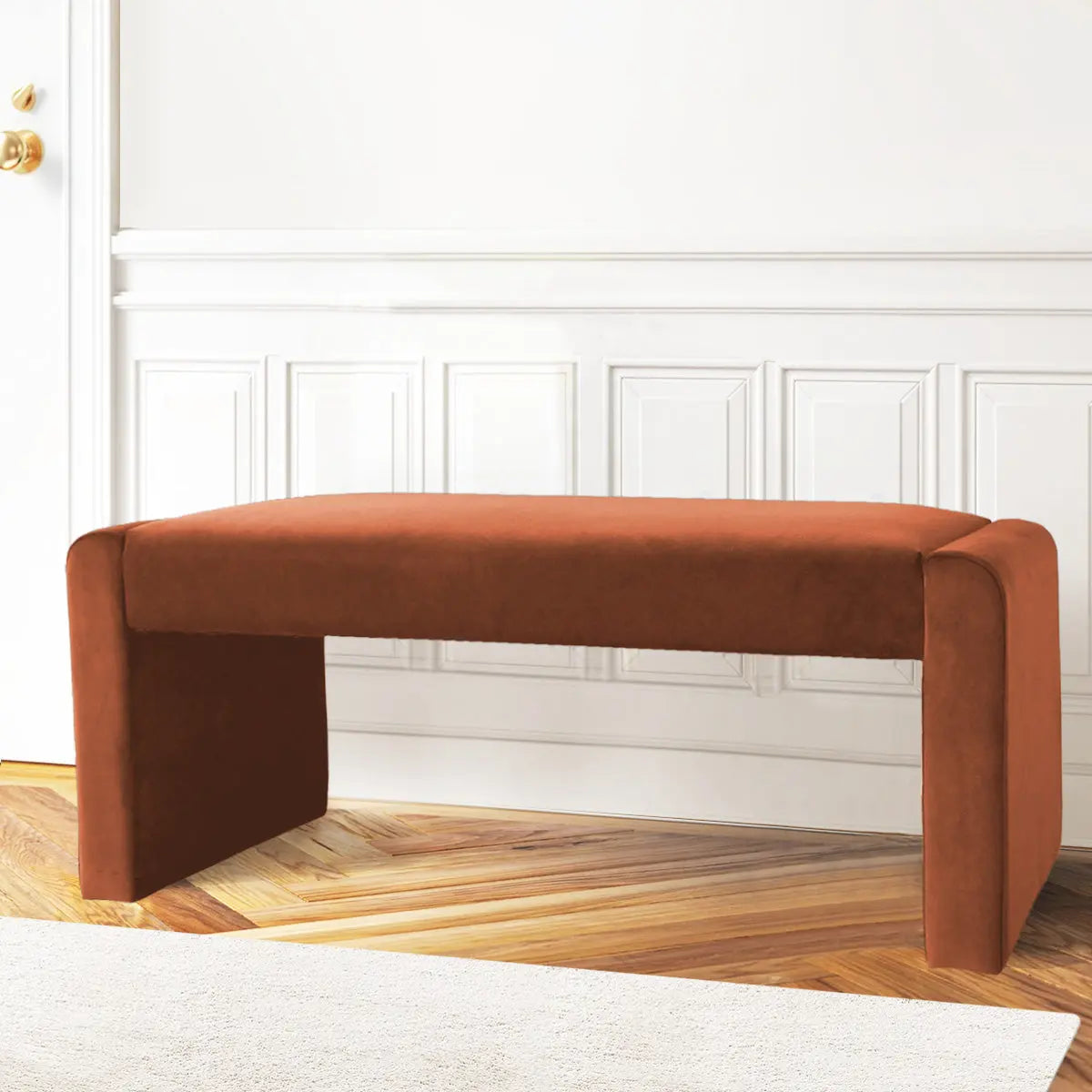 Kaia Modern Waterfall Bench in Velvet, wood flooring, white paneled wall, elegant living room setting.