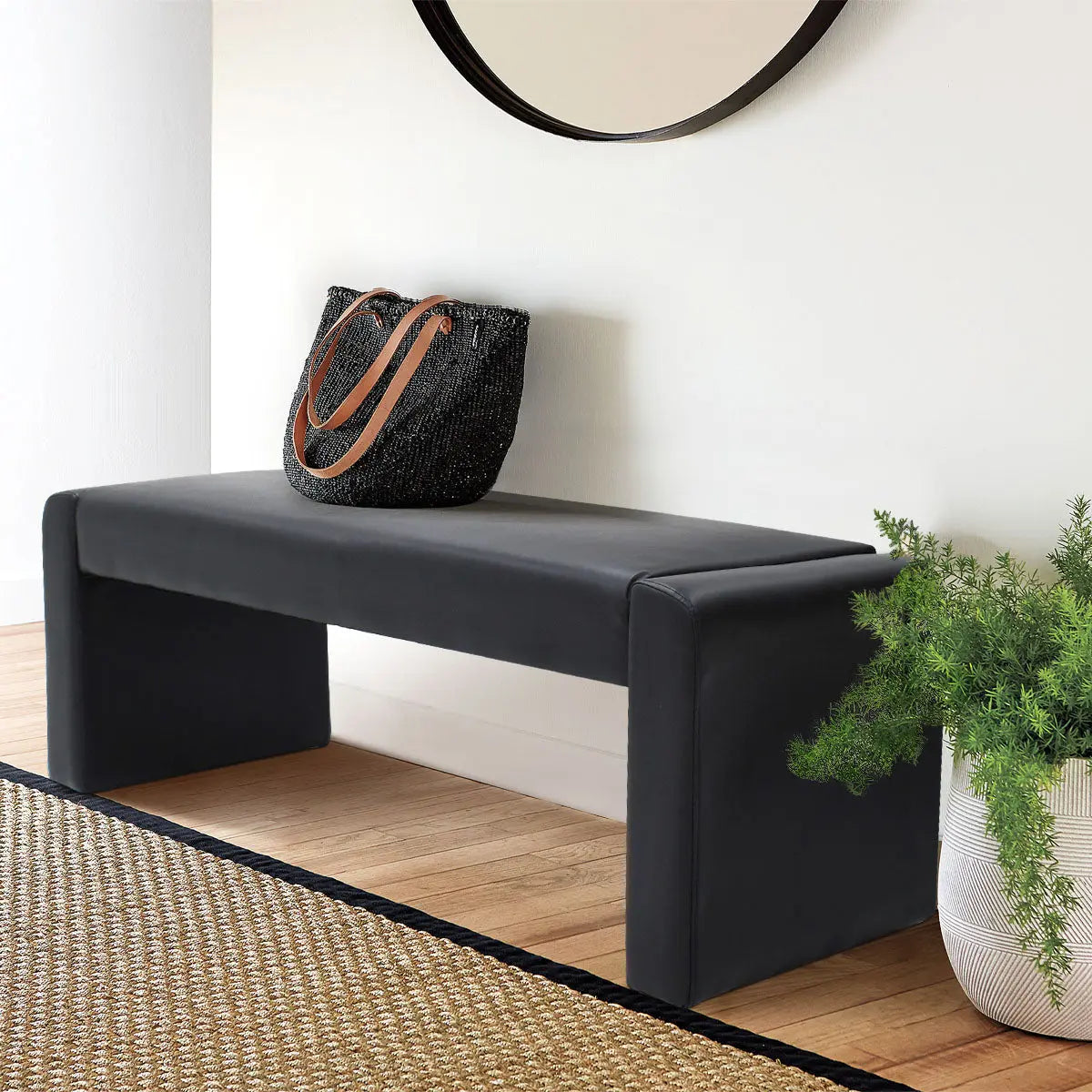 Kaia Modern Leather & Velvet Waterfall Bench in room with light walls, wooden flooring, and mirror.