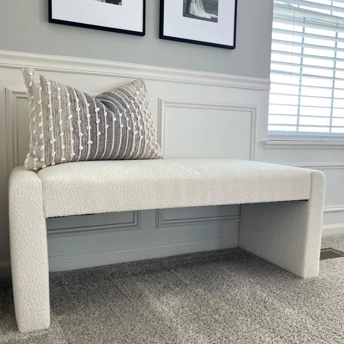 Kaia Modern Beige Upholstered Waterfall Bench, gray wall paneling, carpeted floor, decorative pillow, framed art.