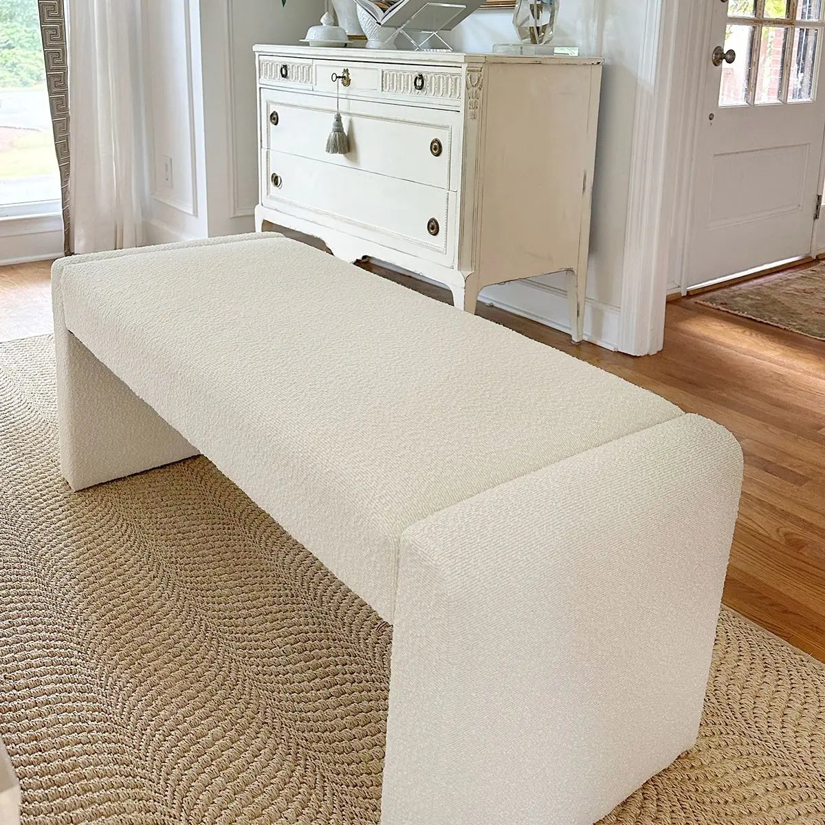 Kaia Modern Beige Upholstered Waterfall Bench, white dresser, woven rug, hardwood floor, classic room.