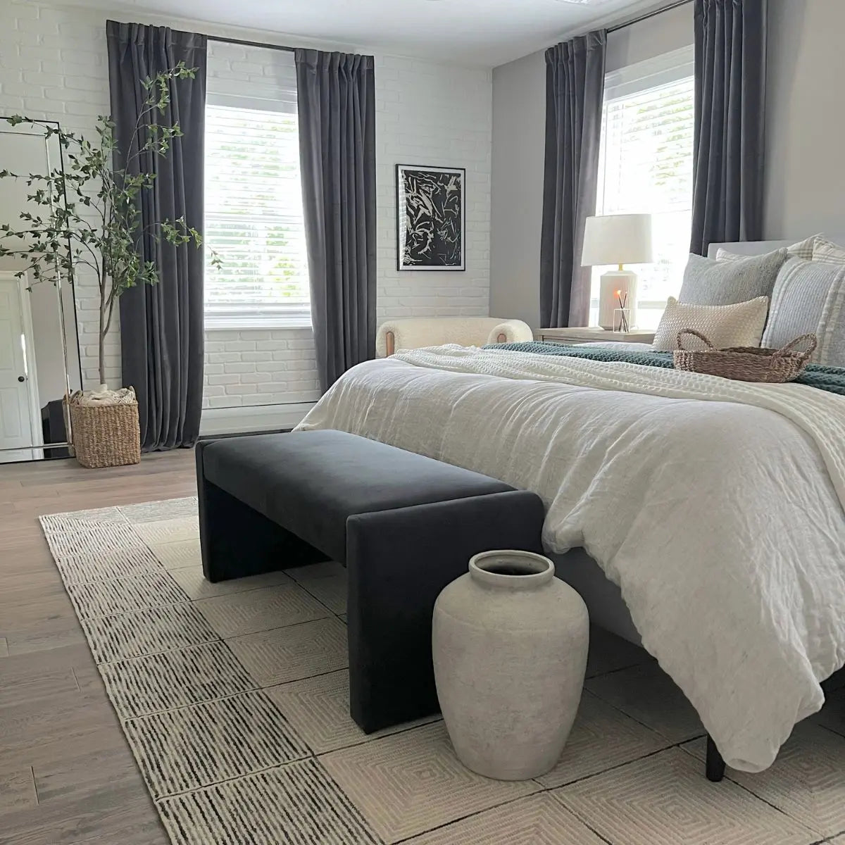 Kaia Modern Leather Velvet Waterfall Bench in bedroom with gray curtains, white brick wall, and vase.