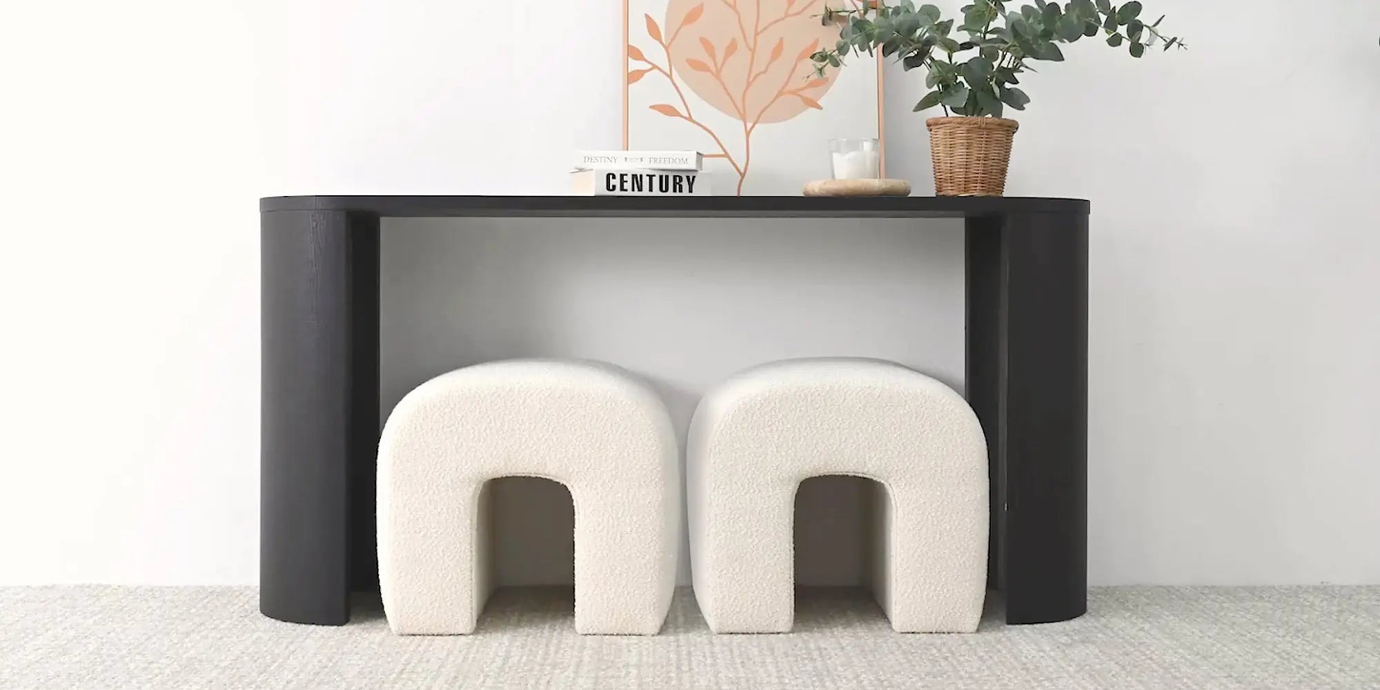 Lily Beige Boucle Waterfall Ottoman under black console table on light carpet.