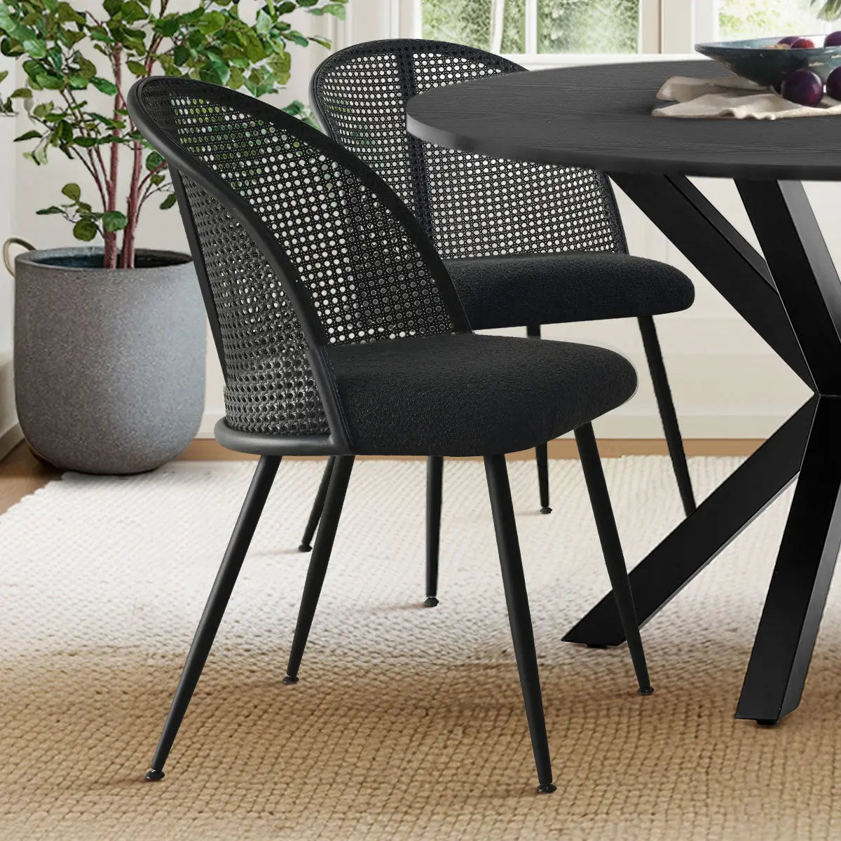 Lucca black dining chairs, rattan boucle, with modern table on textured rug in bright dining room.