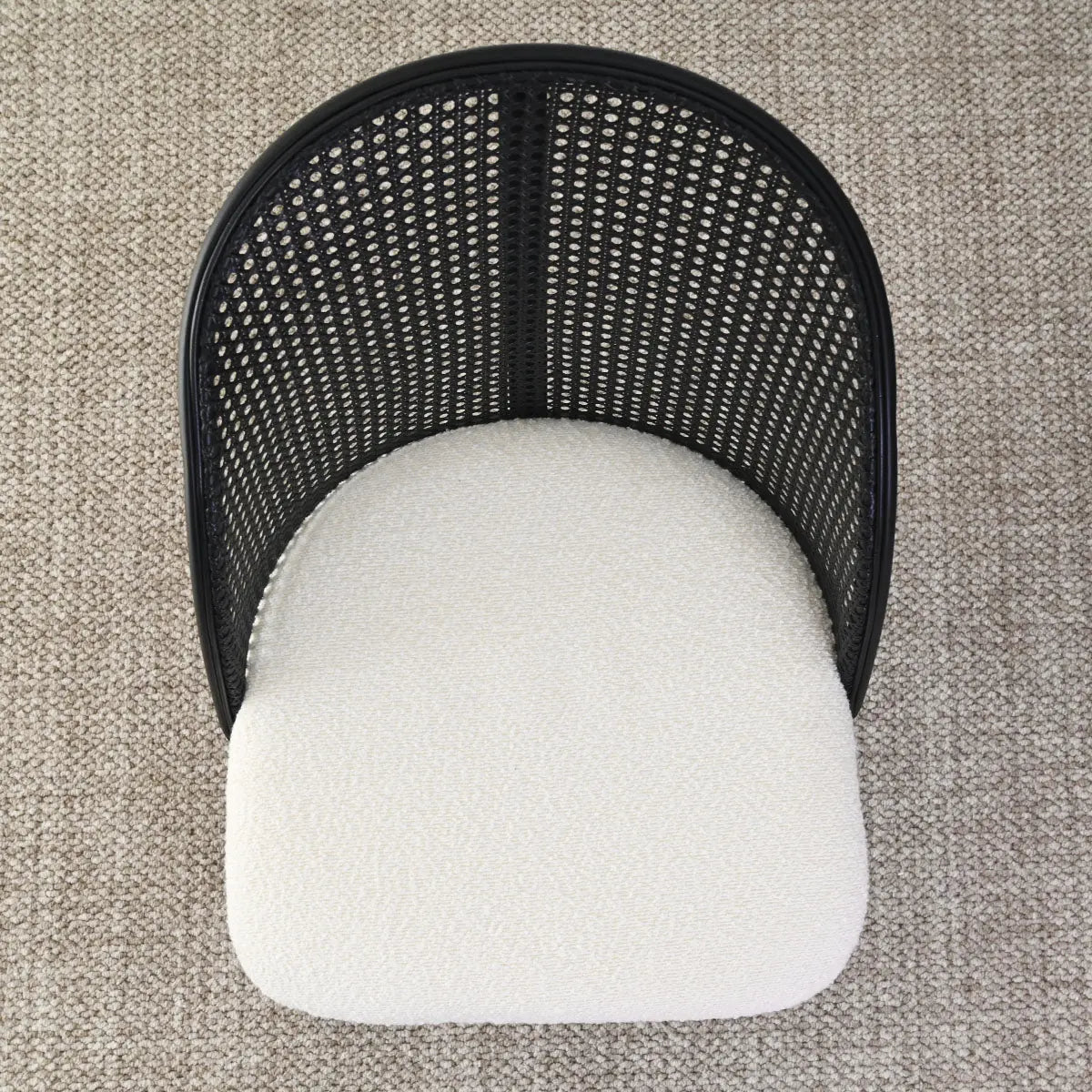 Top view of Lucca Black Rattan Boucle Dining Chair on beige carpet flooring.