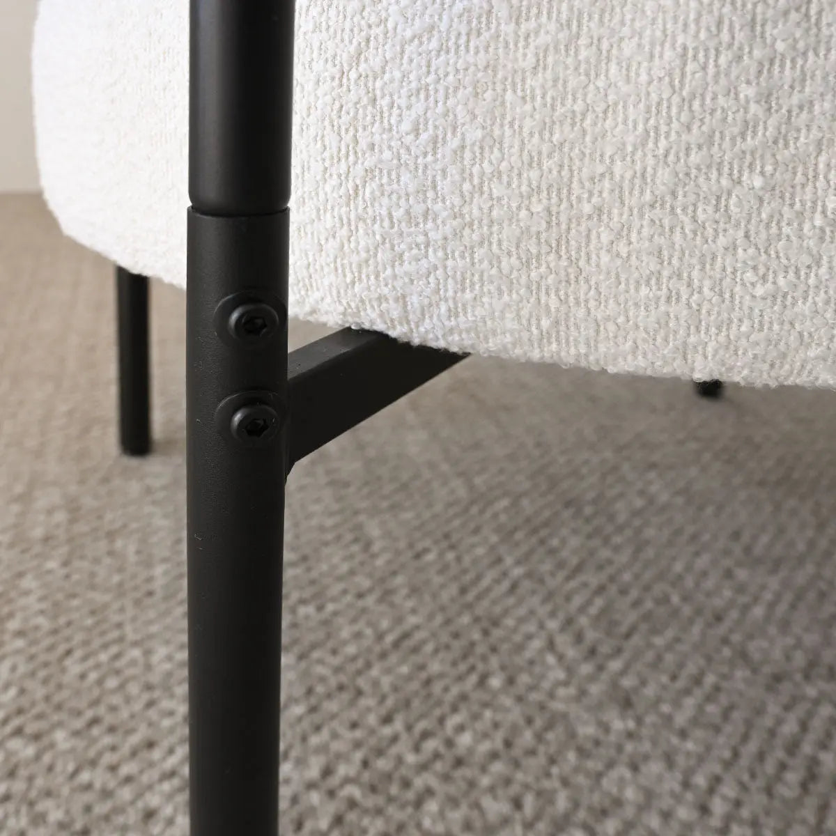 Close-up of Marse Boucle Barrel Accent Chair leg on textured carpet flooring.