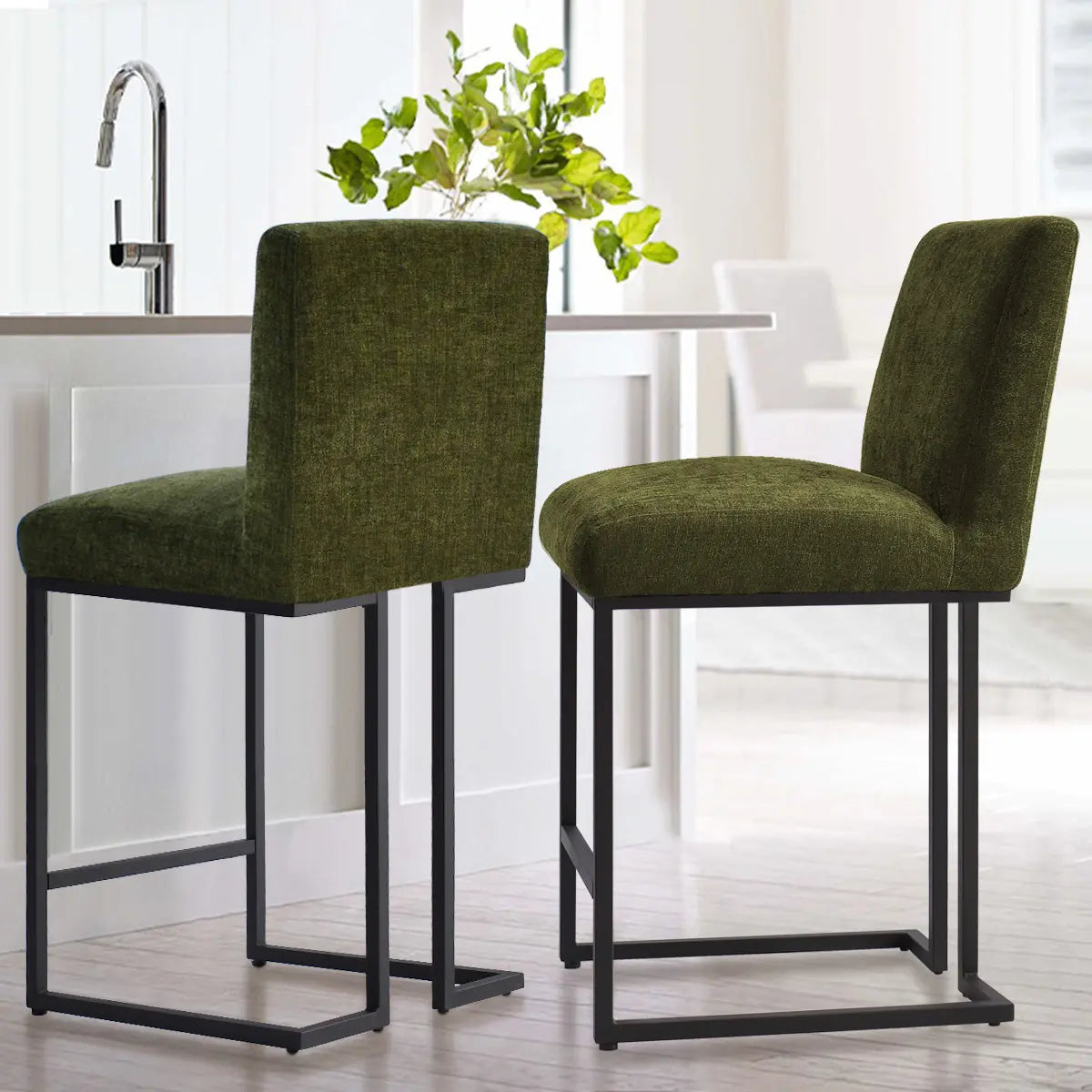 Green upholstered counter stools with modern metal frames, white kitchen, light wood flooring.