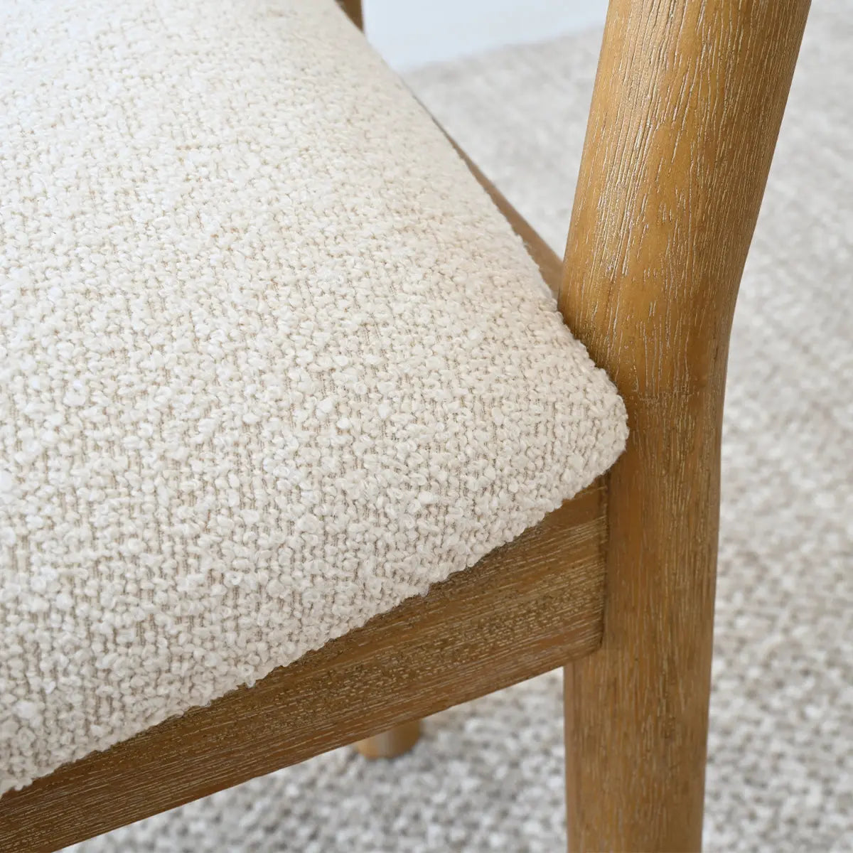 Close-up of Maye Boucle Beige Upholstered Dining Chair with wooden frame and textured fabric.