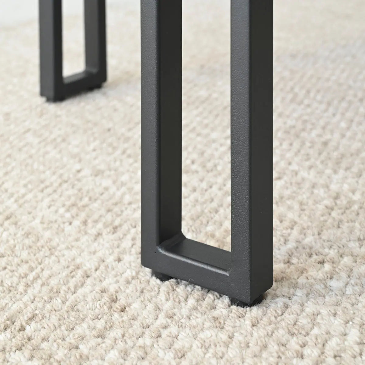 Close-up of black metal legs on carpet, Mia Beige Upholstered Curved-Back Dining Chair with Arms.