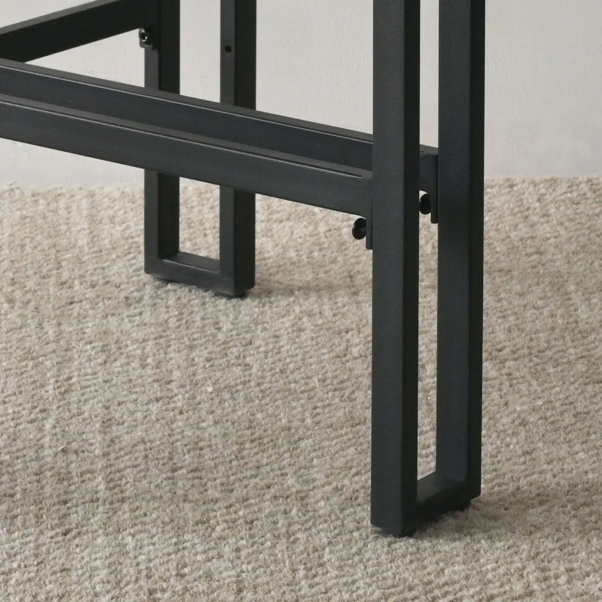 Close-up of Mia Modern Beige Upholstered Counter Stool legs on textured beige carpet flooring.