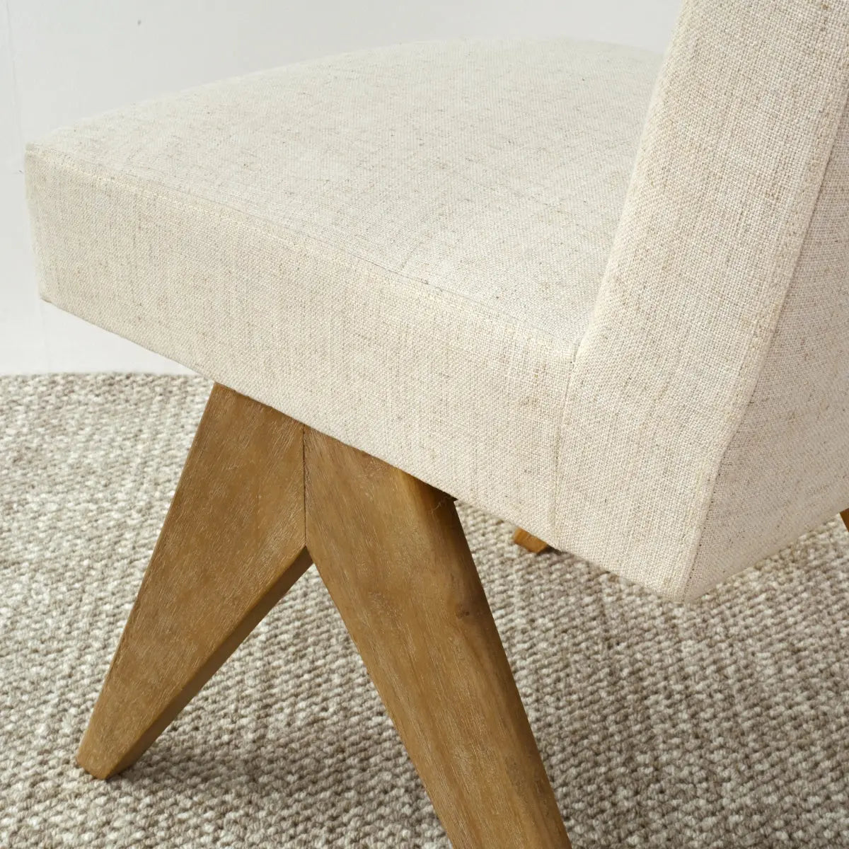 Morgan Mid-Century Boucle Dining Chair with beige upholstery, rustic wooden legs, on textured carpet.