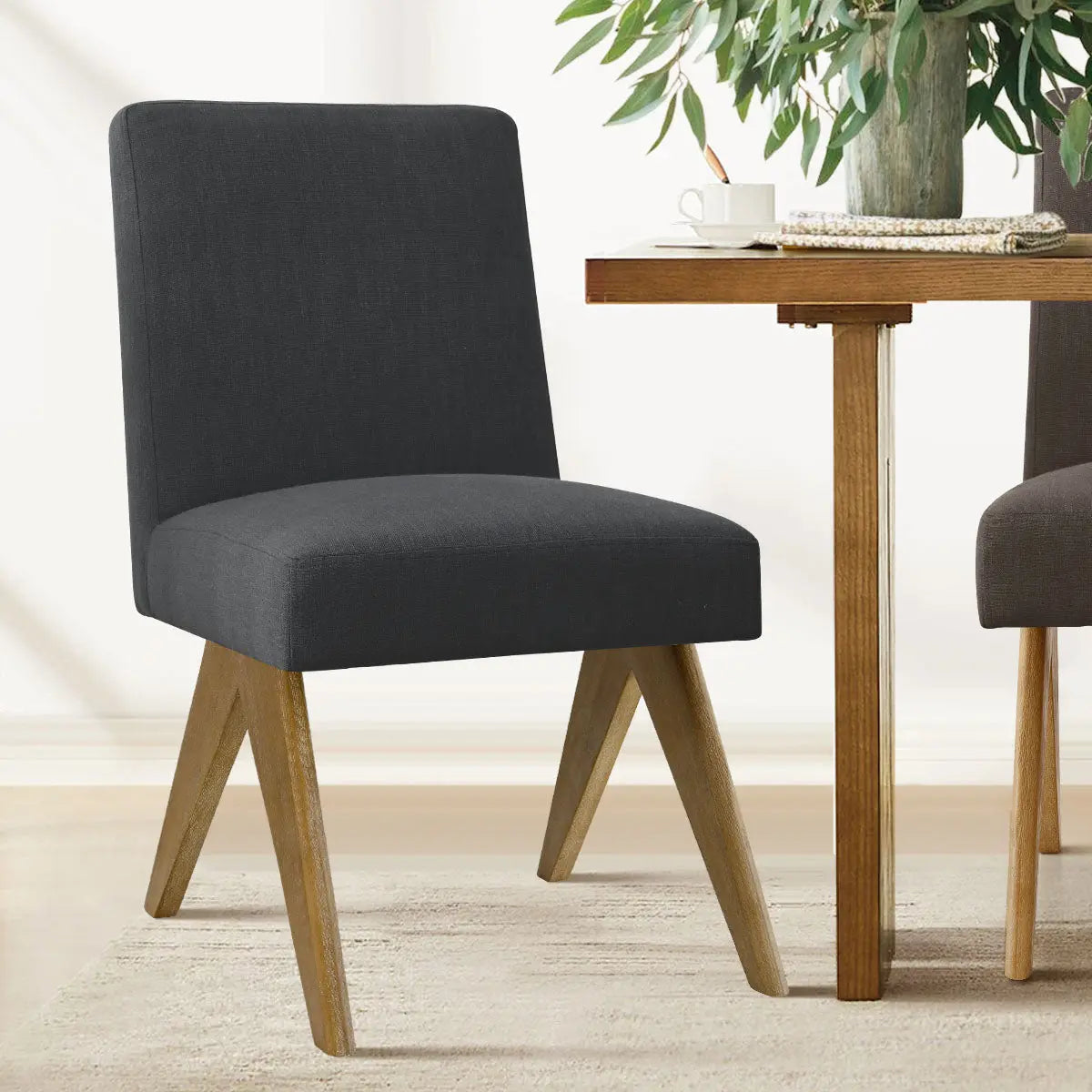 Morgan Mid-Century Boucle Upholstered Dining Chair next to wooden table, light carpet flooring.