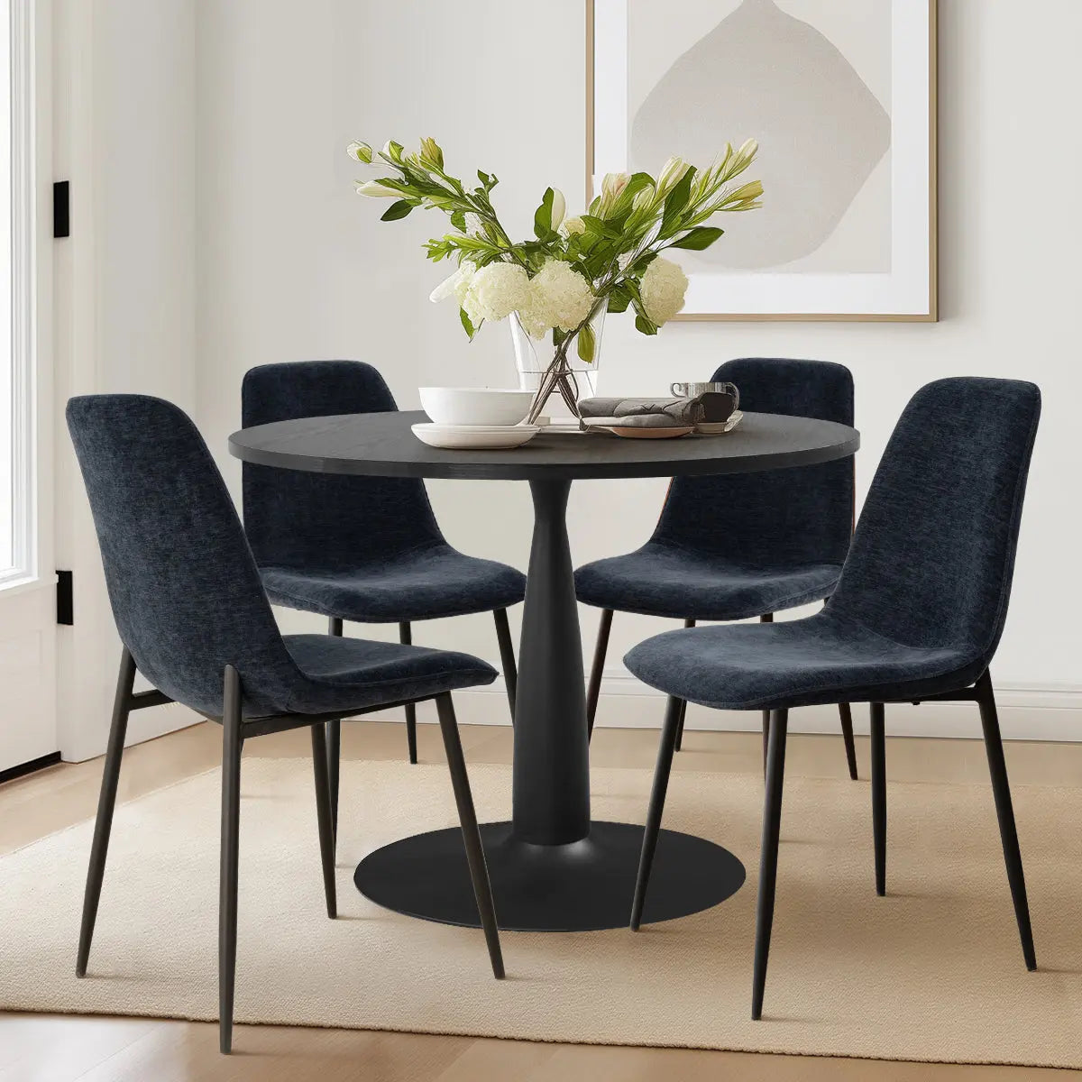 Contemporary dining room featuring Haven & Oslo black round table set with dark chairs on light wood flooring.