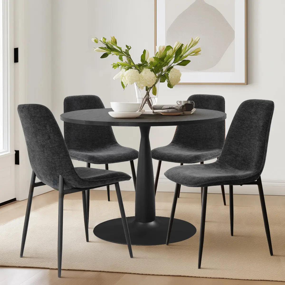 Haven & Oslo dining set with black round table, dark chairs, light walls, and wood flooring.