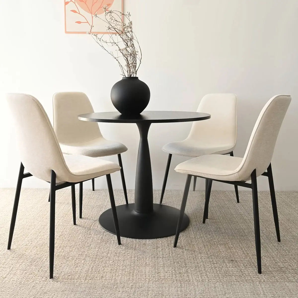 Haven & Oslo 35" black dining set with ivory chairs, textured rug, minimalist decor, light wall.