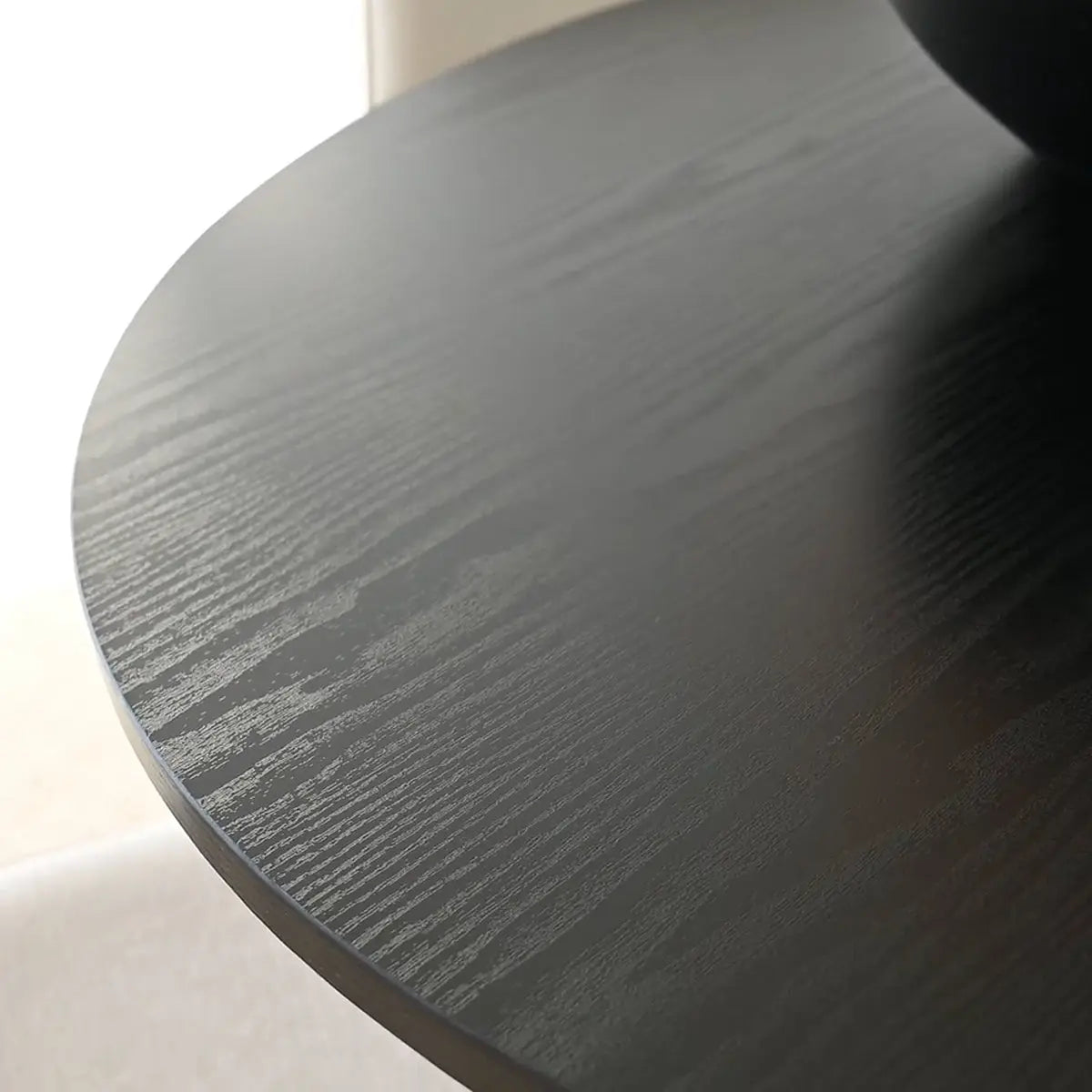 Close-up of Haven & Oslo black round dining table set with wood texture and light background.