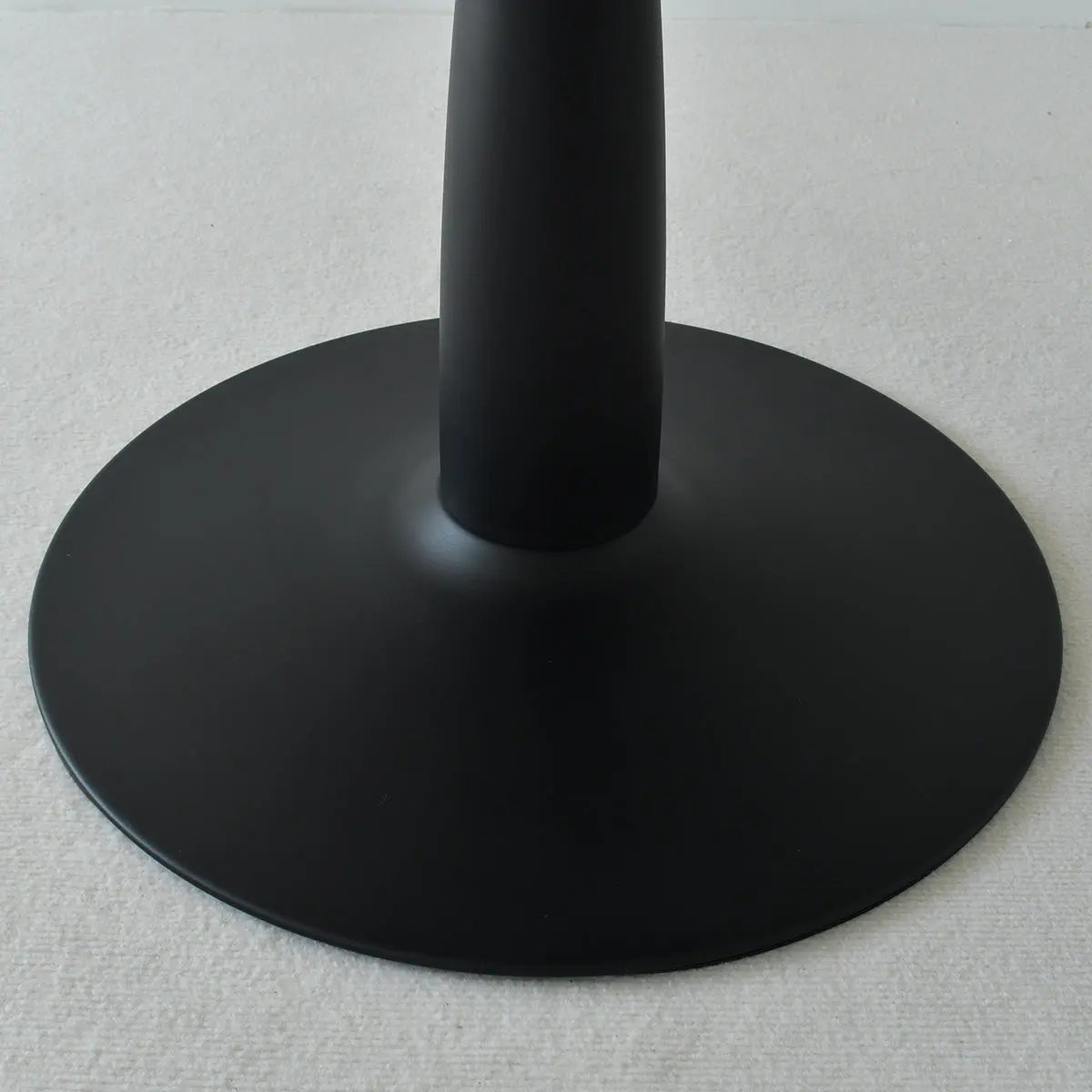 Haven Modern Black Round Table base, minimalist design, close-up view on neutral flooring.