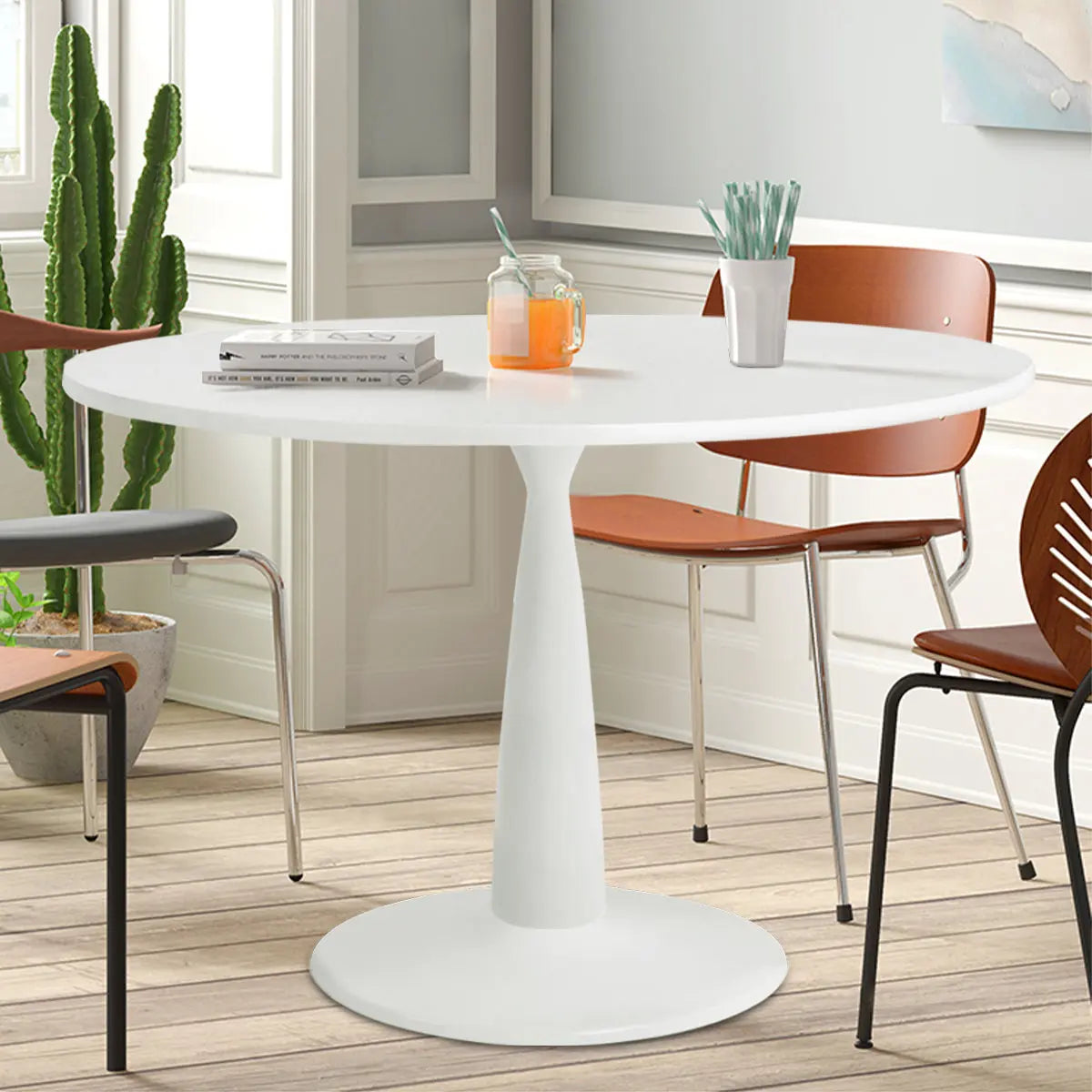 Haven Modern round dining table with brown chairs, light wooden floor, white panel wall, cactus decor.