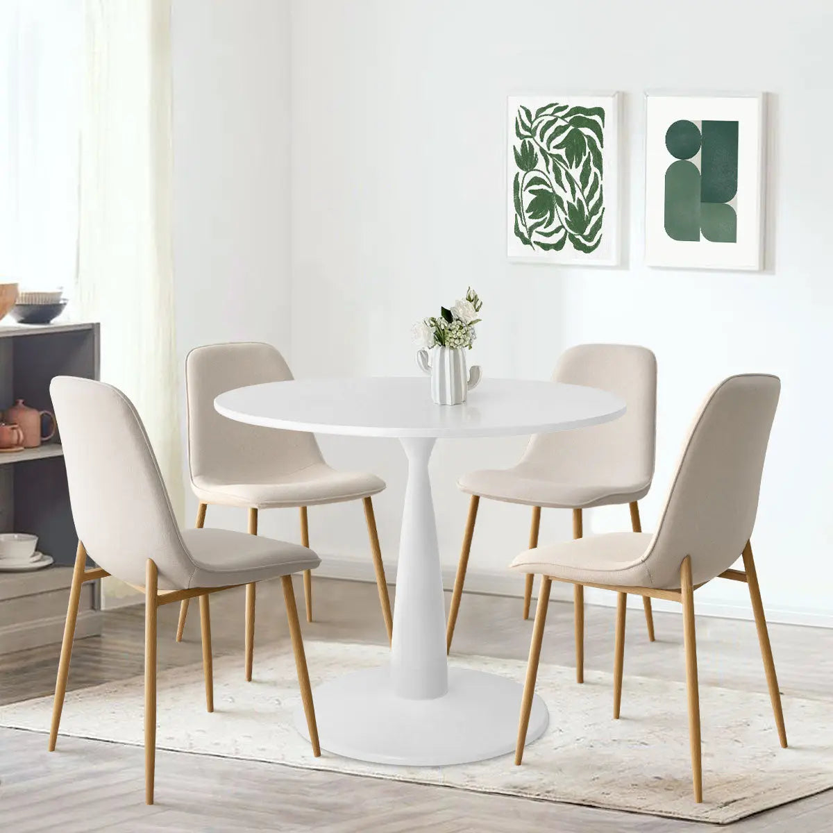 Haven & Oslo dining set with white round table, beige chairs, art on white wall, hardwood floor.