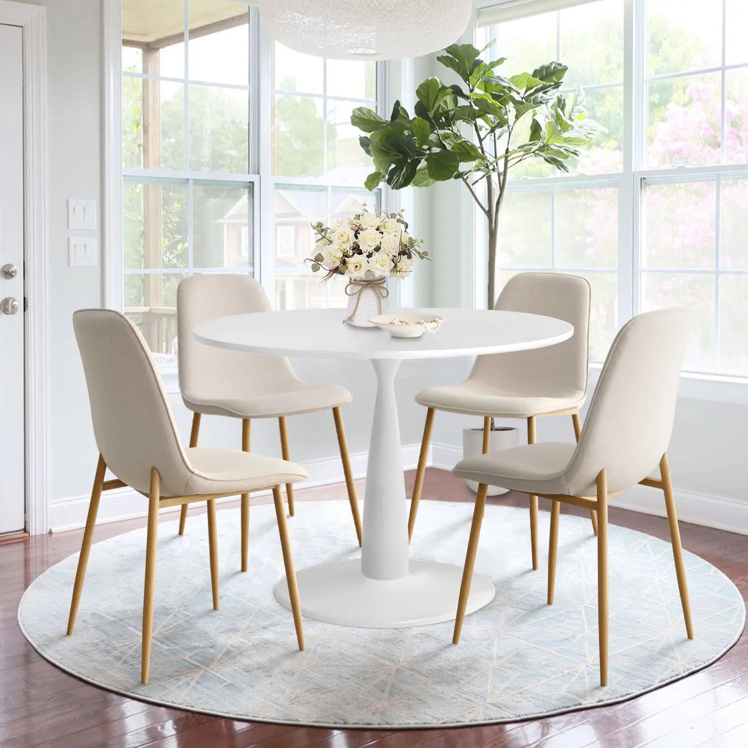 Haven & Oslo white round dining table set with beige chairs, hardwood flooring, and large windows.