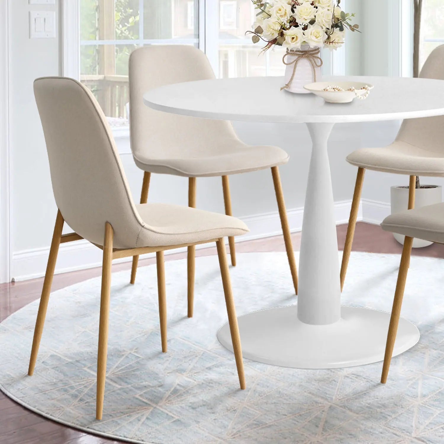 Haven & Oslo dining table set, white round table, wooden chairs, light room, rug, window view.