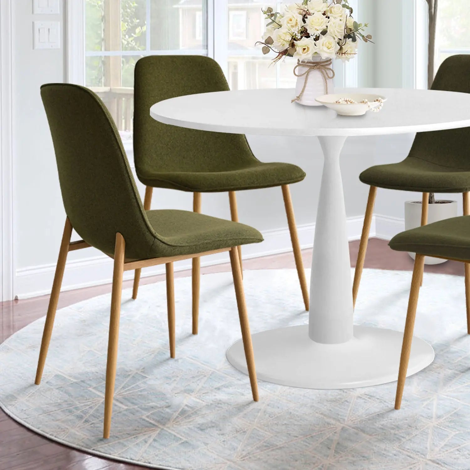 Haven & Oslo dining table set with olive chairs, white walls, round rug, hardwood floor, modern decor.