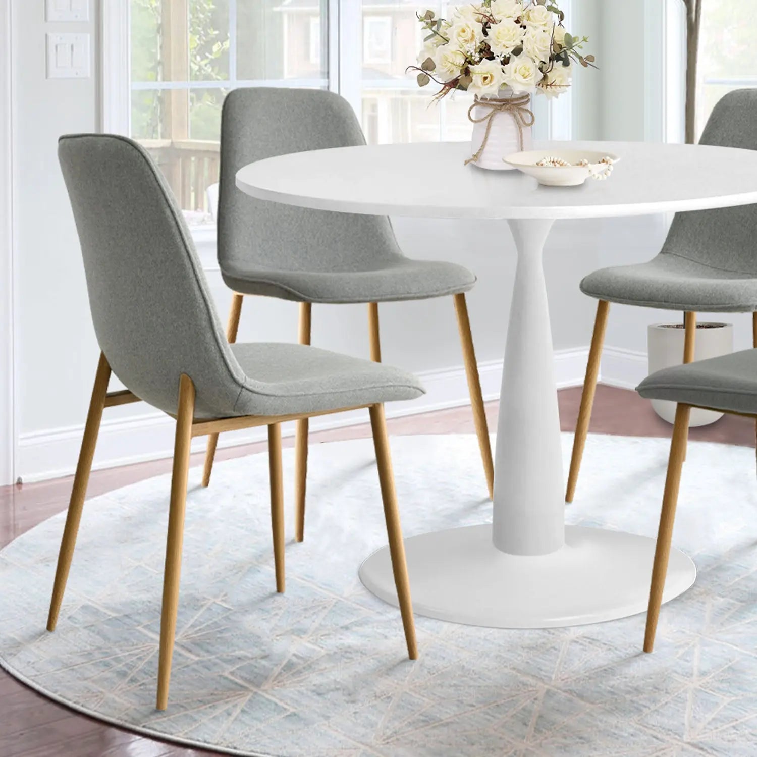 Haven & Oslo round dining set with grey chairs, white table on patterned rug in bright room.