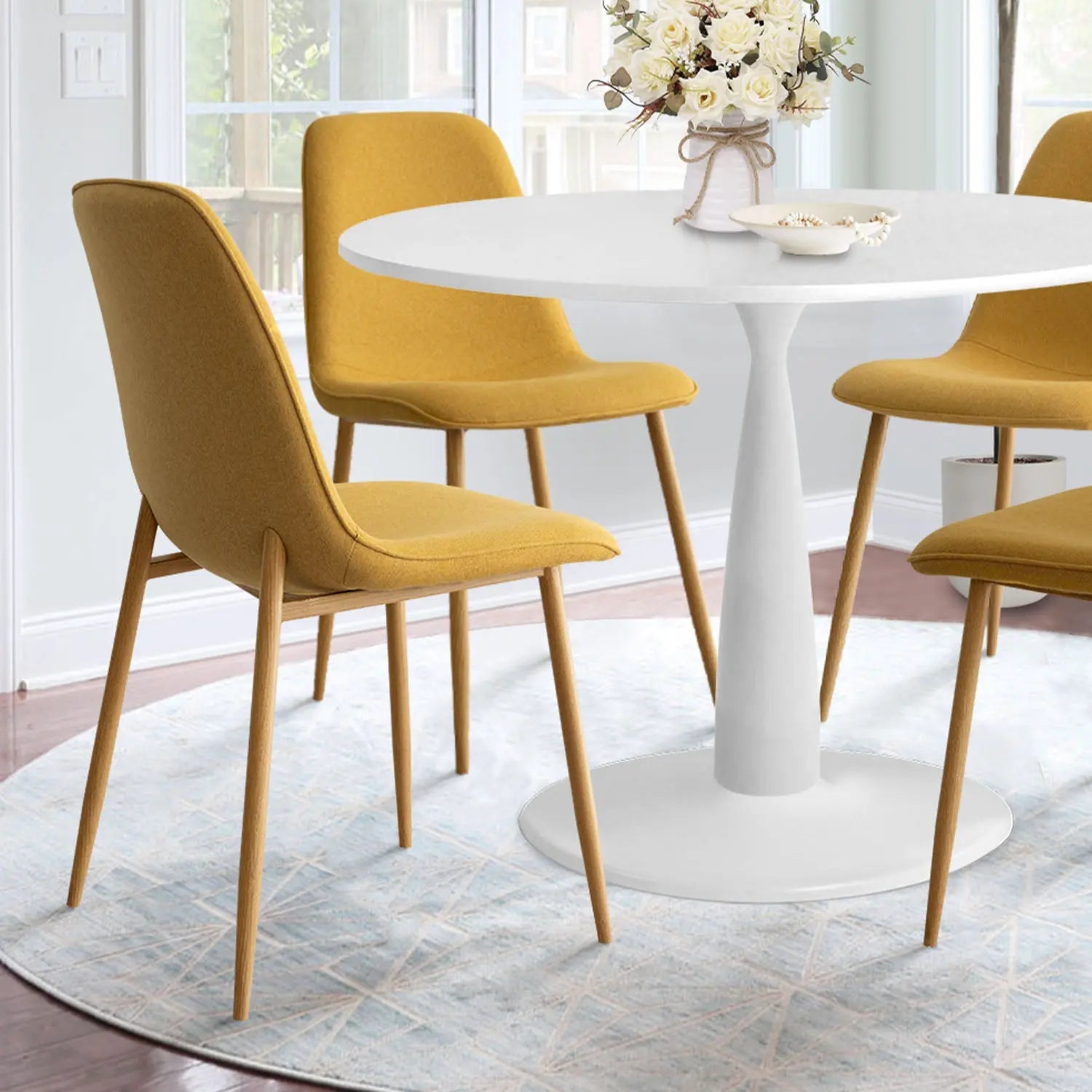 Haven & Oslo dining set with white round table, mustard chairs, light walls, on hardwood flooring.