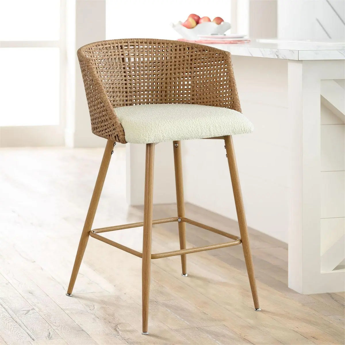 Beige rattan counter stool with upholstered seat in kitchen setting, light wood flooring, white island.