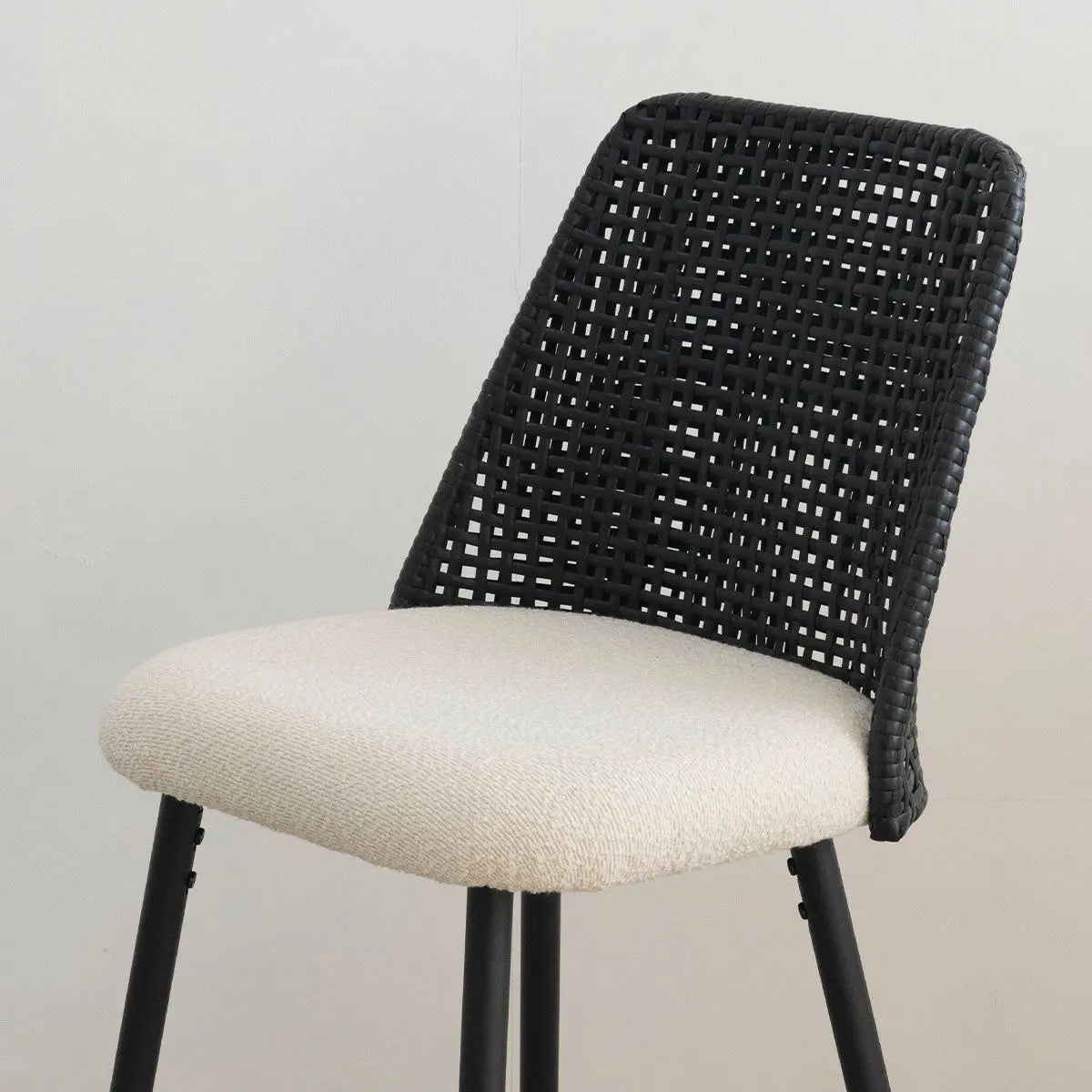 Chic black rattan counter stool with cream upholstery, perfect for modern kitchen or dining rooms.