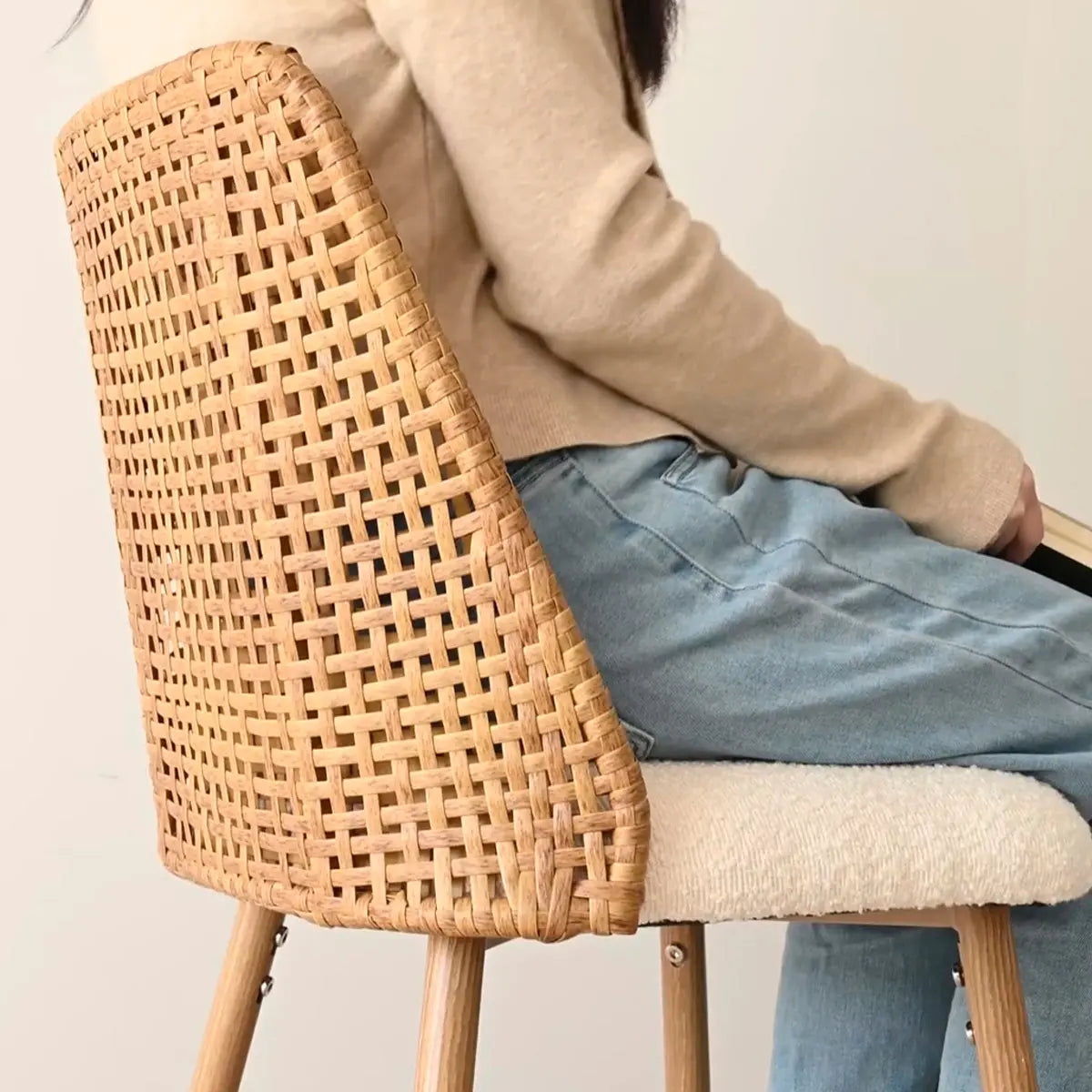 Nice Rattan Upholstered Counter Stool with beige sweater and jeans, modern style.