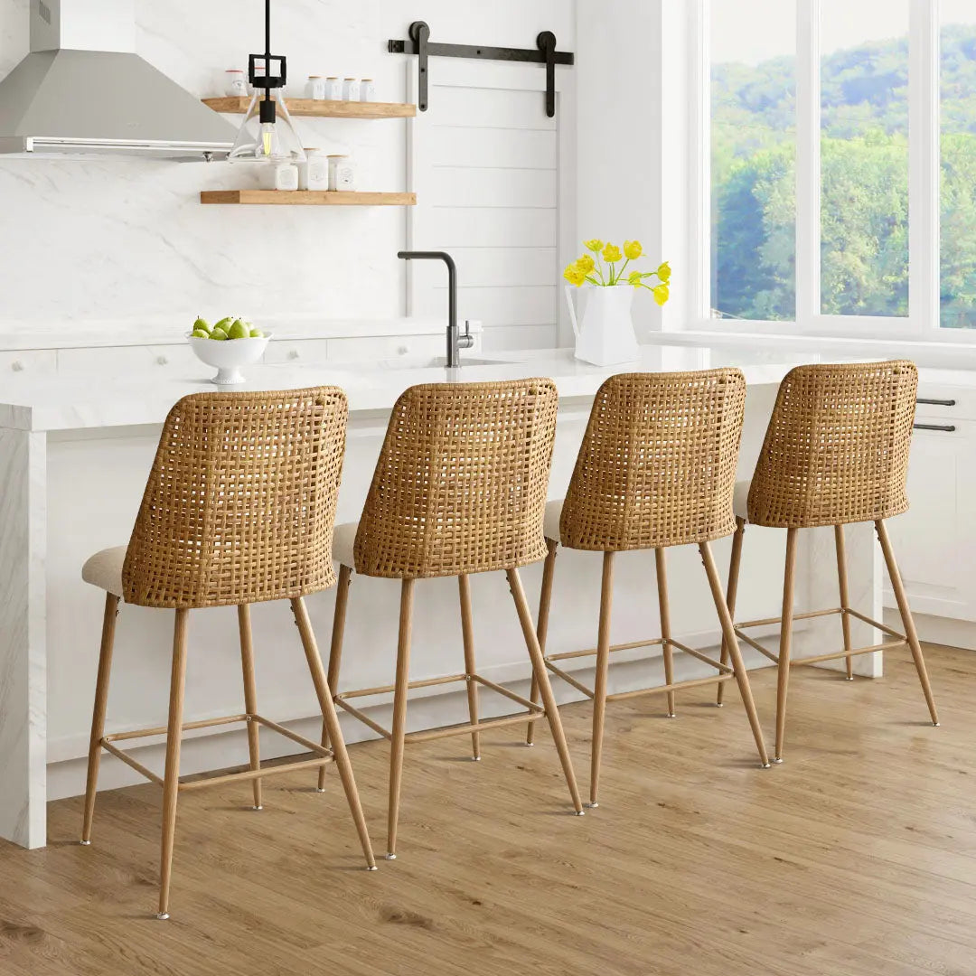 Rattan upholstered counter stool in modern kitchen with wood flooring, white cabinets, and marble countertops.